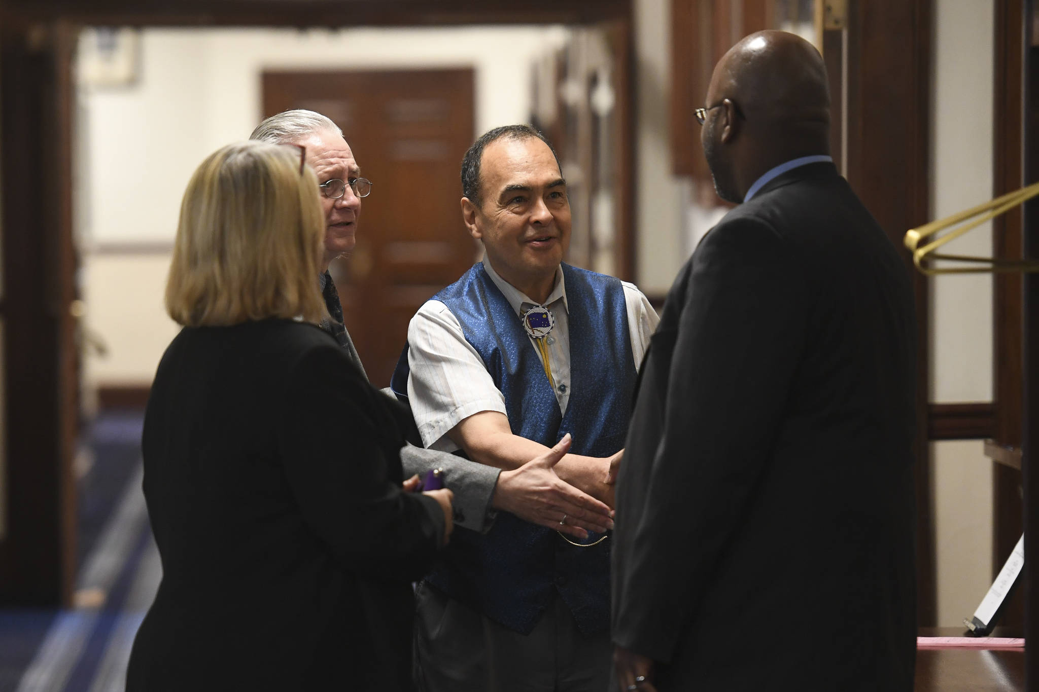 Rep. Tammie Wilson, R-North Pole, left, Sen. Tom Begich, D-Anchorage, and Sen. Donny Olson, D-Golovin, welcome Sen. David Wilson, R-Wasilla, back to the Capitol before a Joint Session of Alaska Legislature at the Capitol on Thursday, July 11, 2019, to debate and vote on an override of Gov. Mike Dunleavy’s budget vetoes. The vote didn’t take place because not enough legislators attended. (Michael Penn | Juneau Empire)