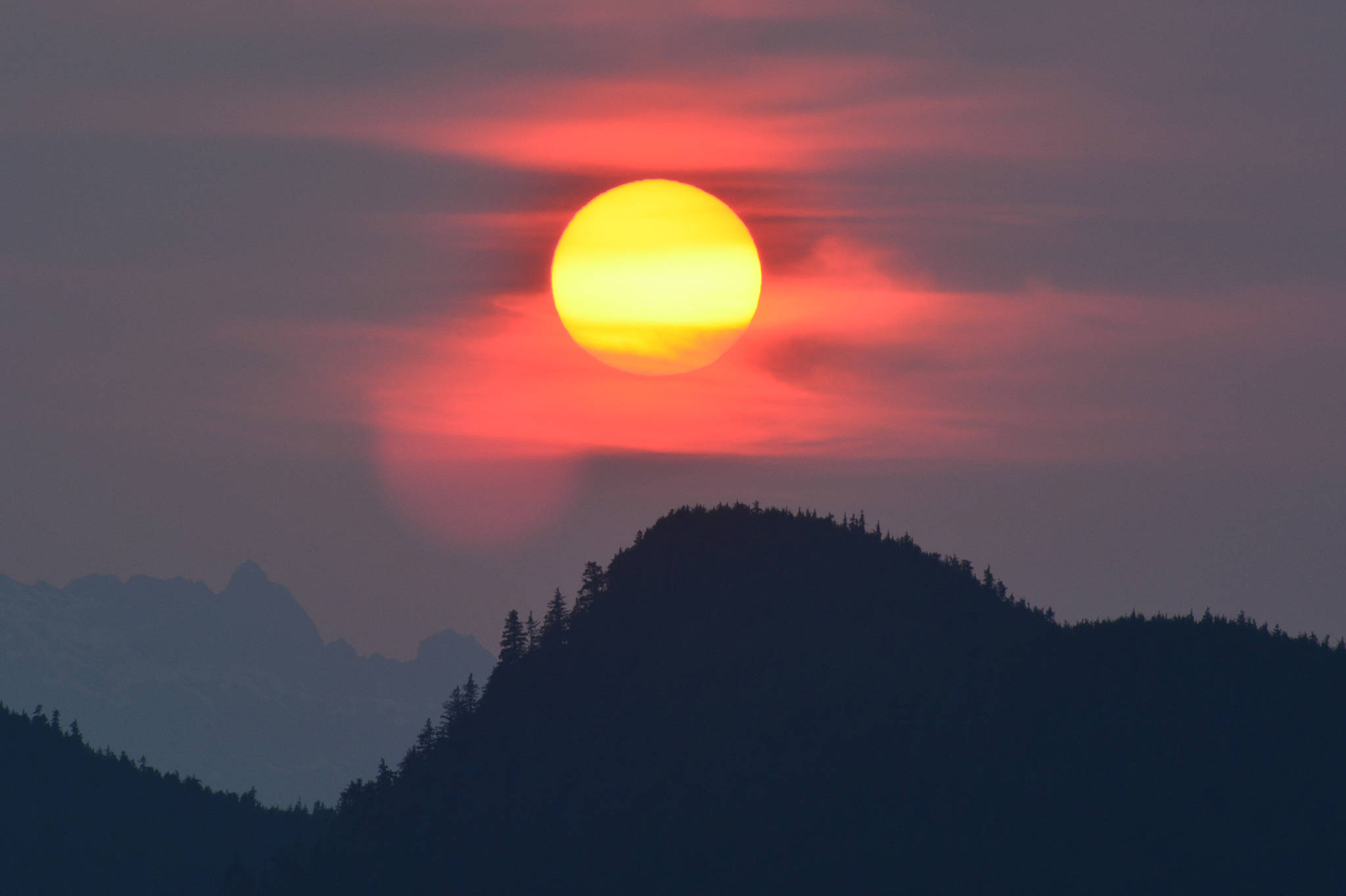 The sun sets over Lincoln Island in the foreground and the Chilkat Peninsula mountains in the background during the recent smoke and haze event that affected the Juneau area. The photo was taken in the Saginaw Channel area on June 30, 2019. (Courtesy Photo | Jerry Reinwand)