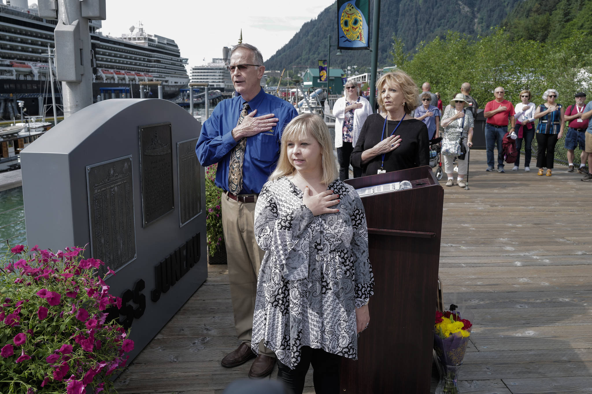 Ashley DeRamus, of Hoover, Alabama, leads the Pledge of Allegiance with her mother, Connie, and Juneau Port Director Carl Uchytil during a ceremony at the U.S.S. Juneau Memorial on the Seawalk on Monday, July 22, 2019. DeRamus, who has Down syndrome, has recited the Pledge and sung the Nation Anthem in all 50 states with Alaska being her 50th on Monday. DeRamus, through her Ashley DeRamus Foundation, works to increase awareness of Down syndrome and enlighten others about the rewards and positive contributions those with Down syndrome make to society. (Michael Penn | Juneau Empire)