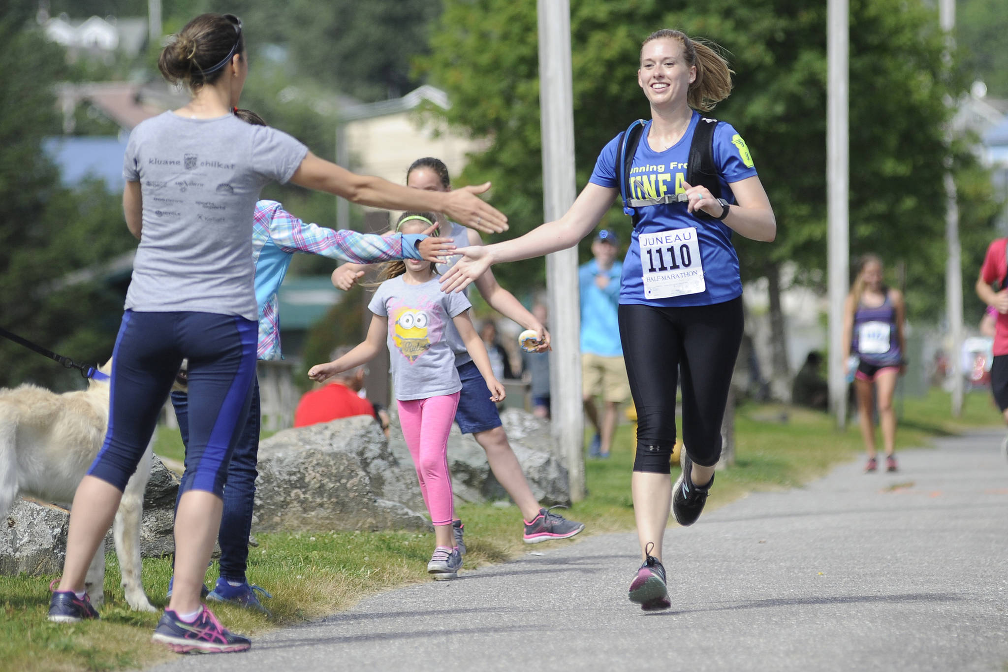 Nicole Gorle high fives a spectator while finishing the Juneau Half Marathon at Savikko Park on Saturday, July 28, 2018. (Nolin Ainsworth | Juneau Empire)