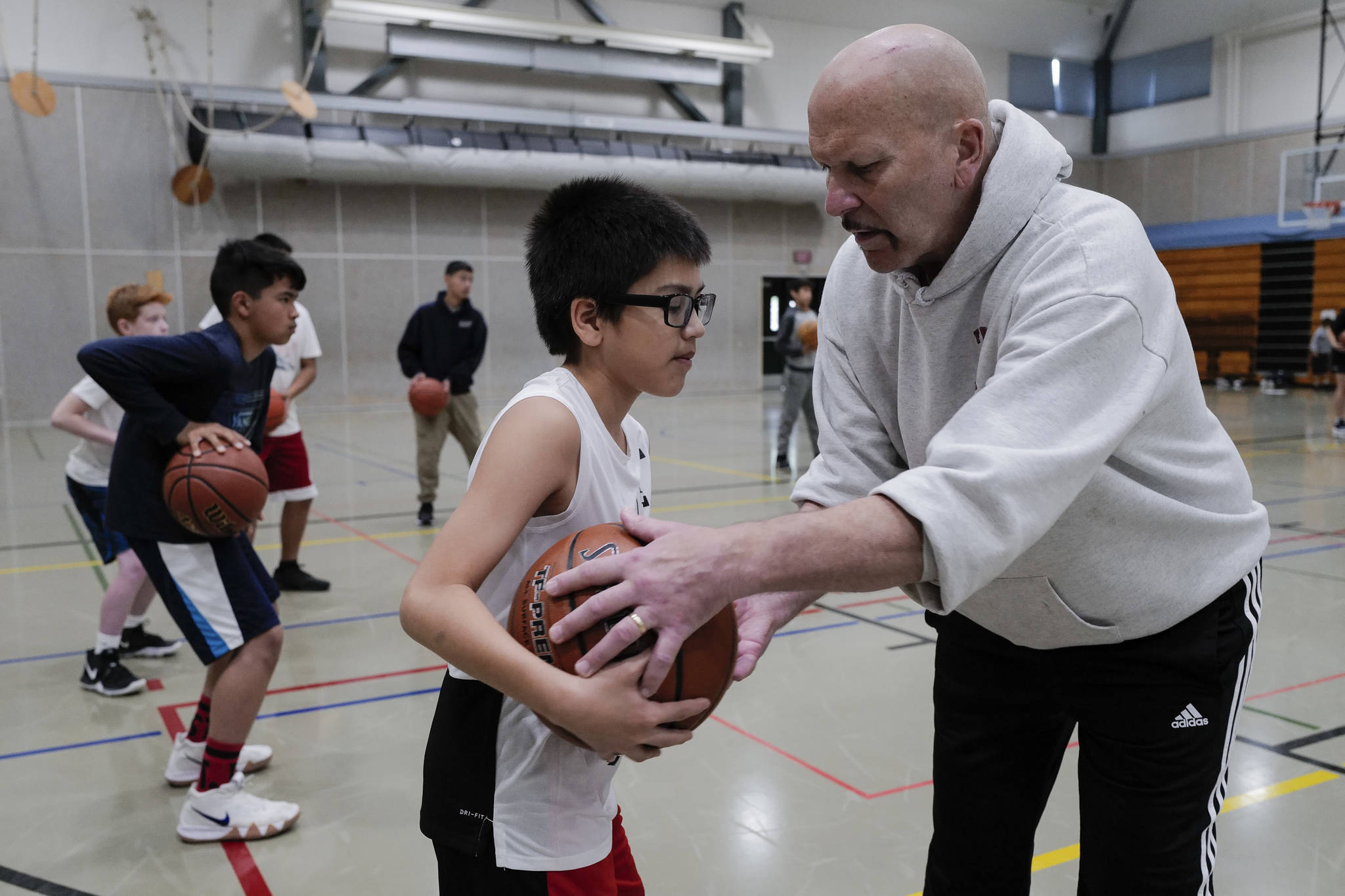 Coach Bob Saviers helps David Friday, 11, with his three-point stance during the Latseen Hoop Camp at Dzantak’i Heeni Middle School on Monday, July 29, 2019. The camp runs all week for students entering grades 6-12. (Michael Penn | Juneau Empire)