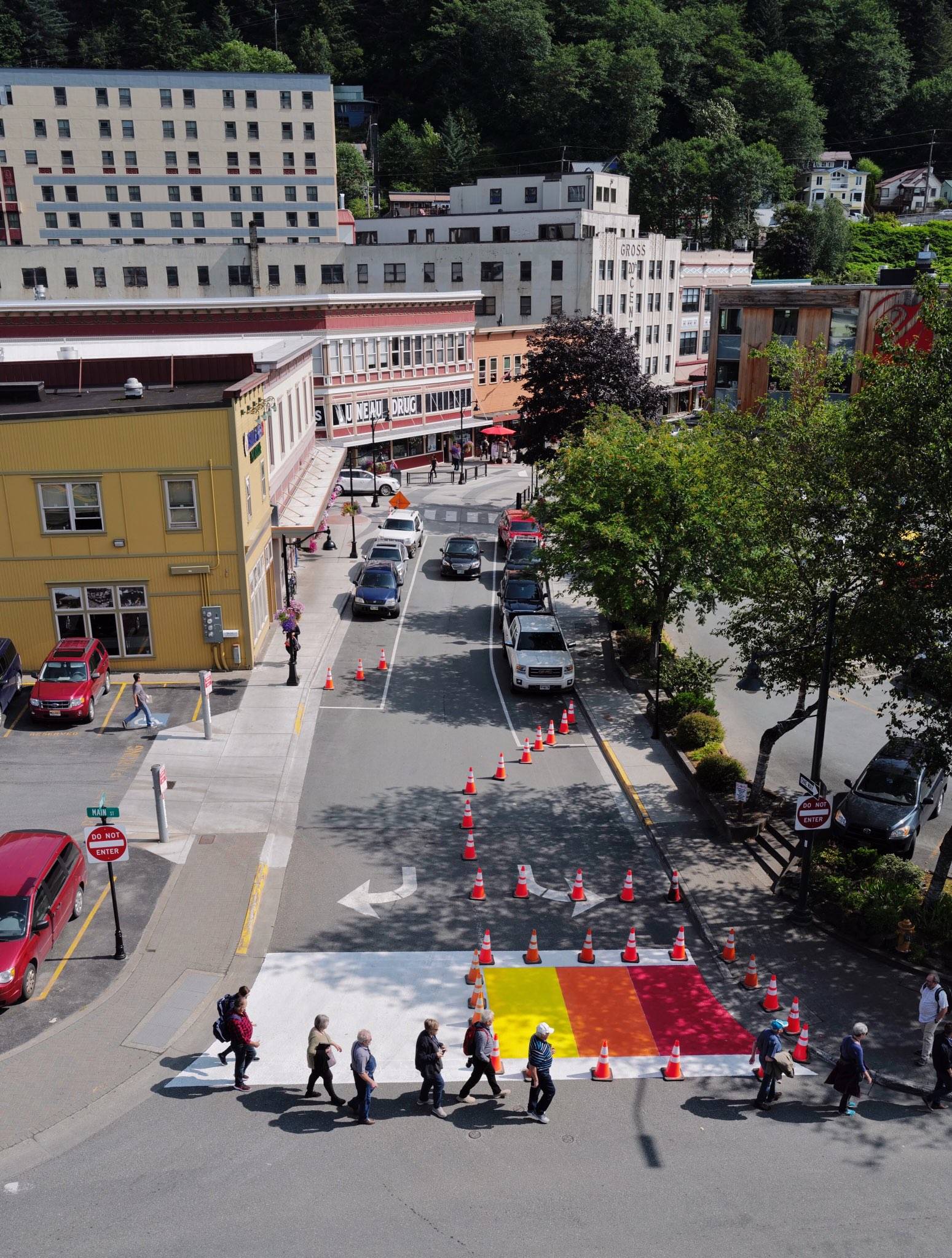 Pedestrians cross Front Street at Main where the city is in the middle of a multi-day project to paint the crosswalk in rainbow colors on Wednesday, July 31, 2019. (Michael Penn | Juneau Empire)