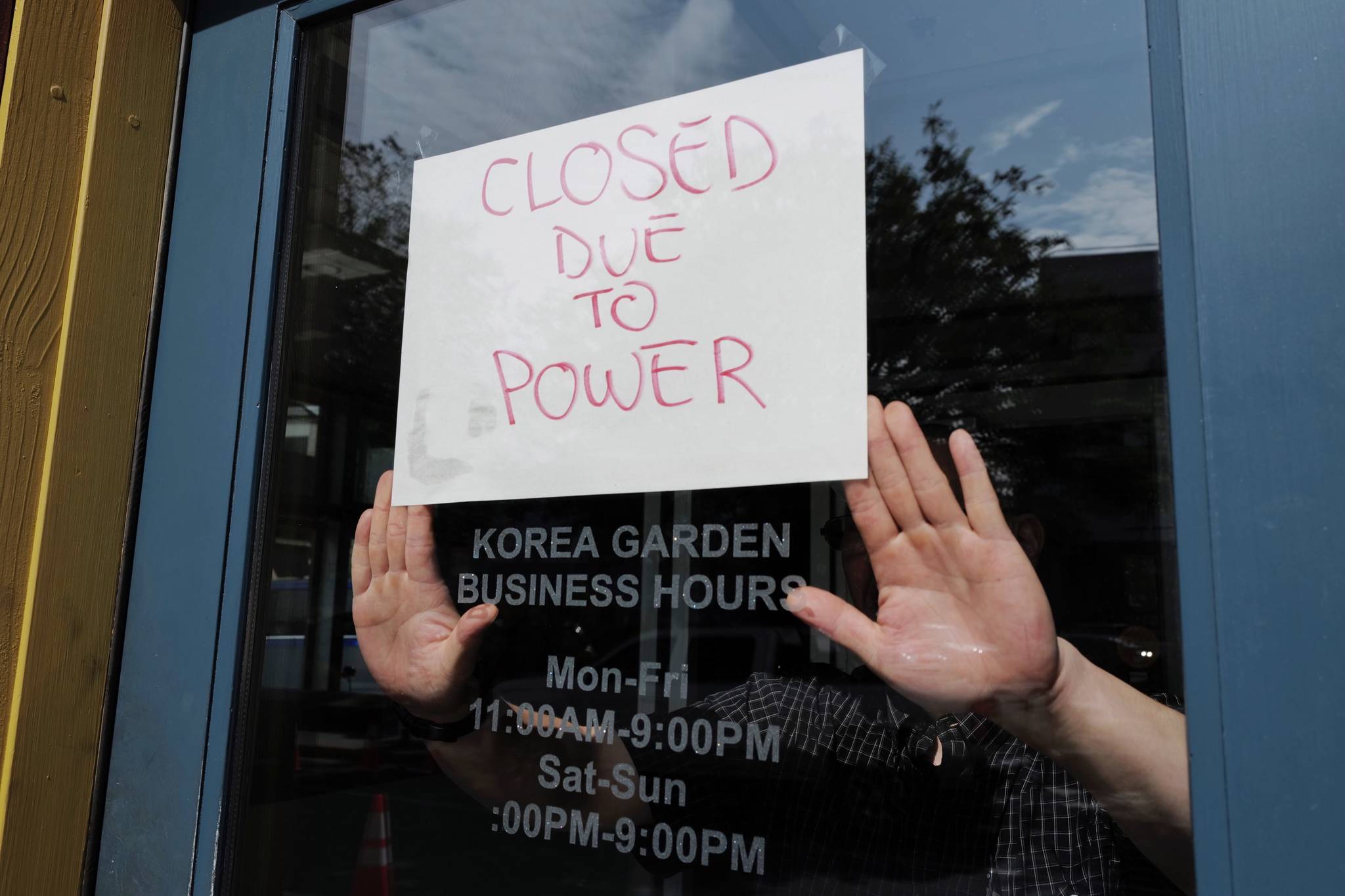 Steven DeVoss, manager of Korea Garden on Front Street, puts up a sign to closed his business before noon on Wednesday, July 31, 2019. (Michael Penn | Juneau Empire)