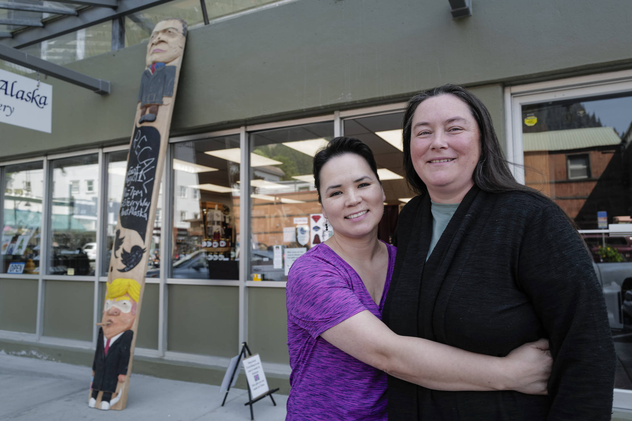 Co-owners Aakatchaq Schaeffer, left, and Vivian Mork Yéilk’ stand in front of their Planet Alaska Gallery with a ridicule pole carved by Sitka artist Tommy Joseph on Wednesday, July 31, 2019. The pole includes likenesses of Alaska Gov. Mike Dunleavy, top, and President Donald Trump. (Michael Penn | Juneau Empire)