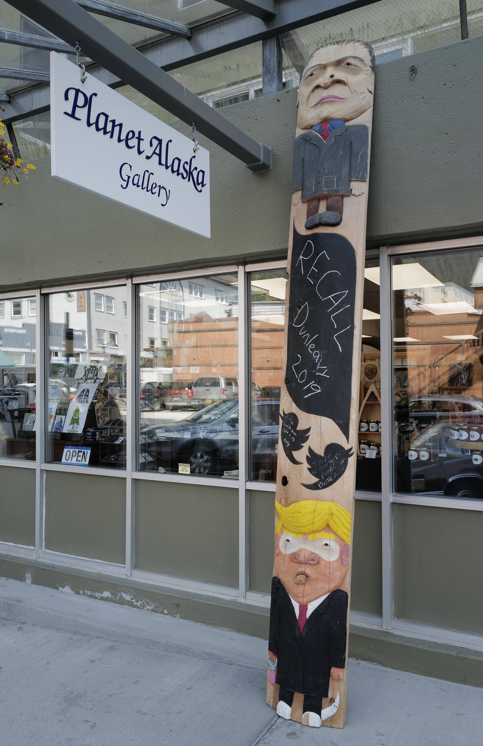A ridicule pole carved by Sitka artist Tommy Joseph stands in front of the Planet Alaska Gallery on Ferry Way on Wednesday, July 31, 2019. The pole includes likenesses of Alaska Gov. Mike Dunleavy, top, and President Donald Trump. (Michael Penn | Juneau Empire)