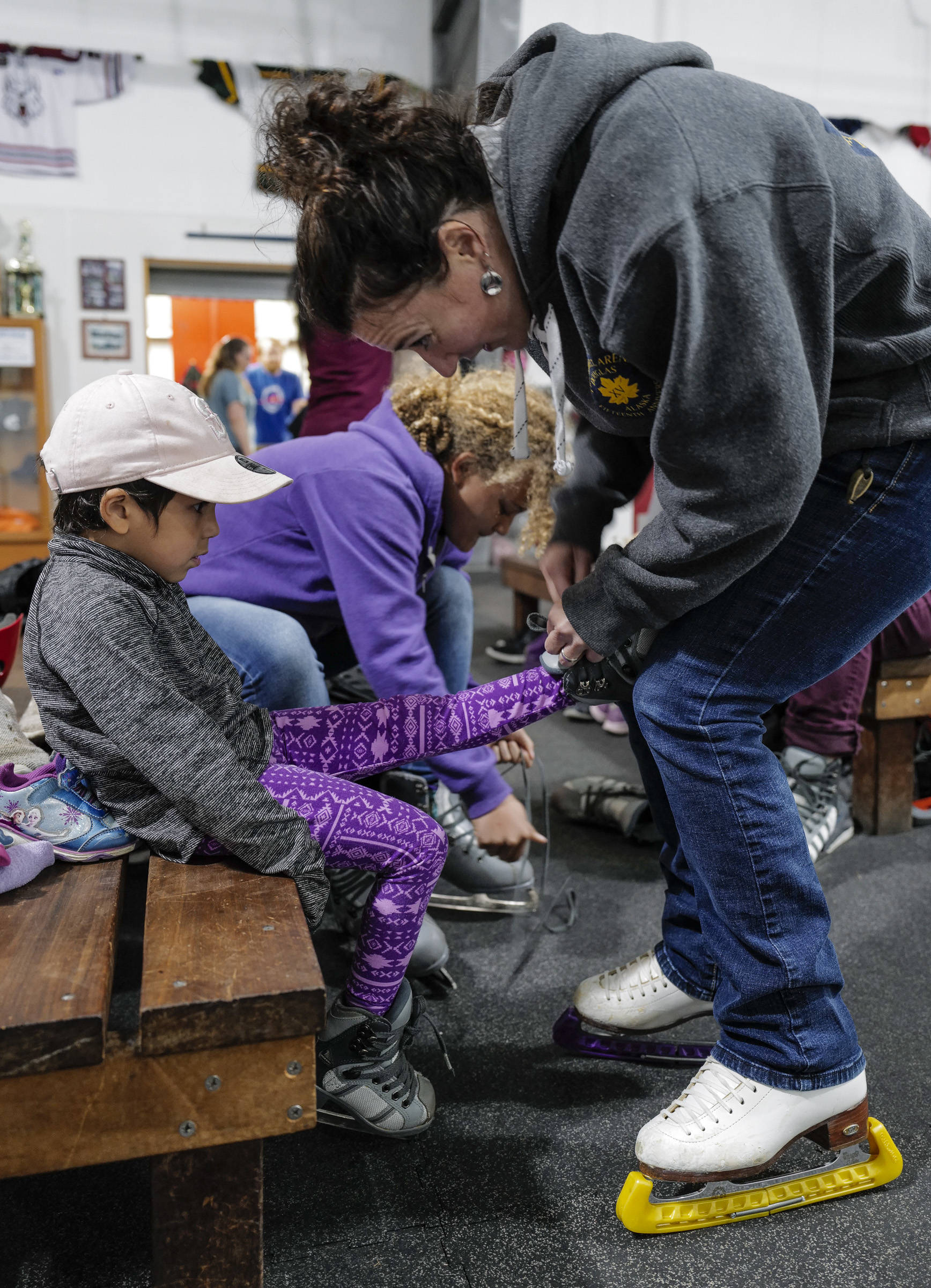 Treadwell Arena Manager Lauren Anderson helps a youngster with her skates during of a free skate on the opening day at the Treadwell Arena on Monday, Aug. 5, 2019. (Michael Penn | Juneau Empire)