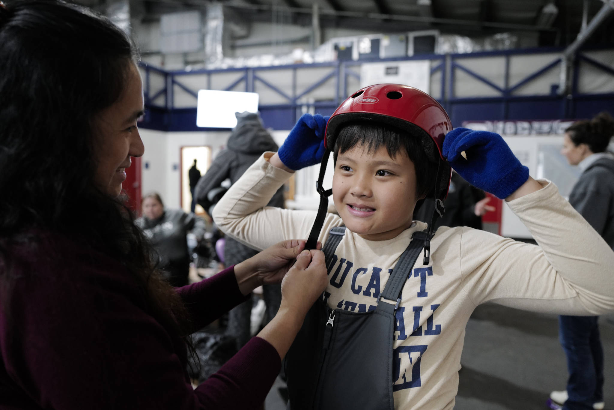Hazel Yadao adjusts a helmet for her son, Arnold, 9, during a free skate on the opening day at the Treadwell Arena on Monday, Aug. 5, 2019. (Michael Penn | Juneau Empire)