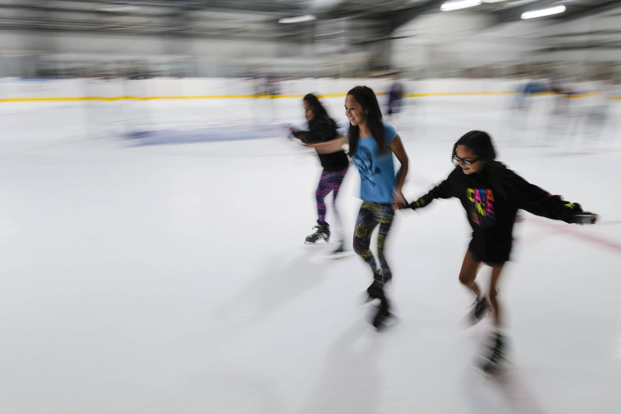 Christianna Lott, 12, left, Lashya Bagoyo, 12, center, and Malaya Willard, 10, hold hands as they skate during a free skate on the opening day at the Treadwell Arena on Monday, Aug. 5, 2019. (Michael Penn | Juneau Empire)