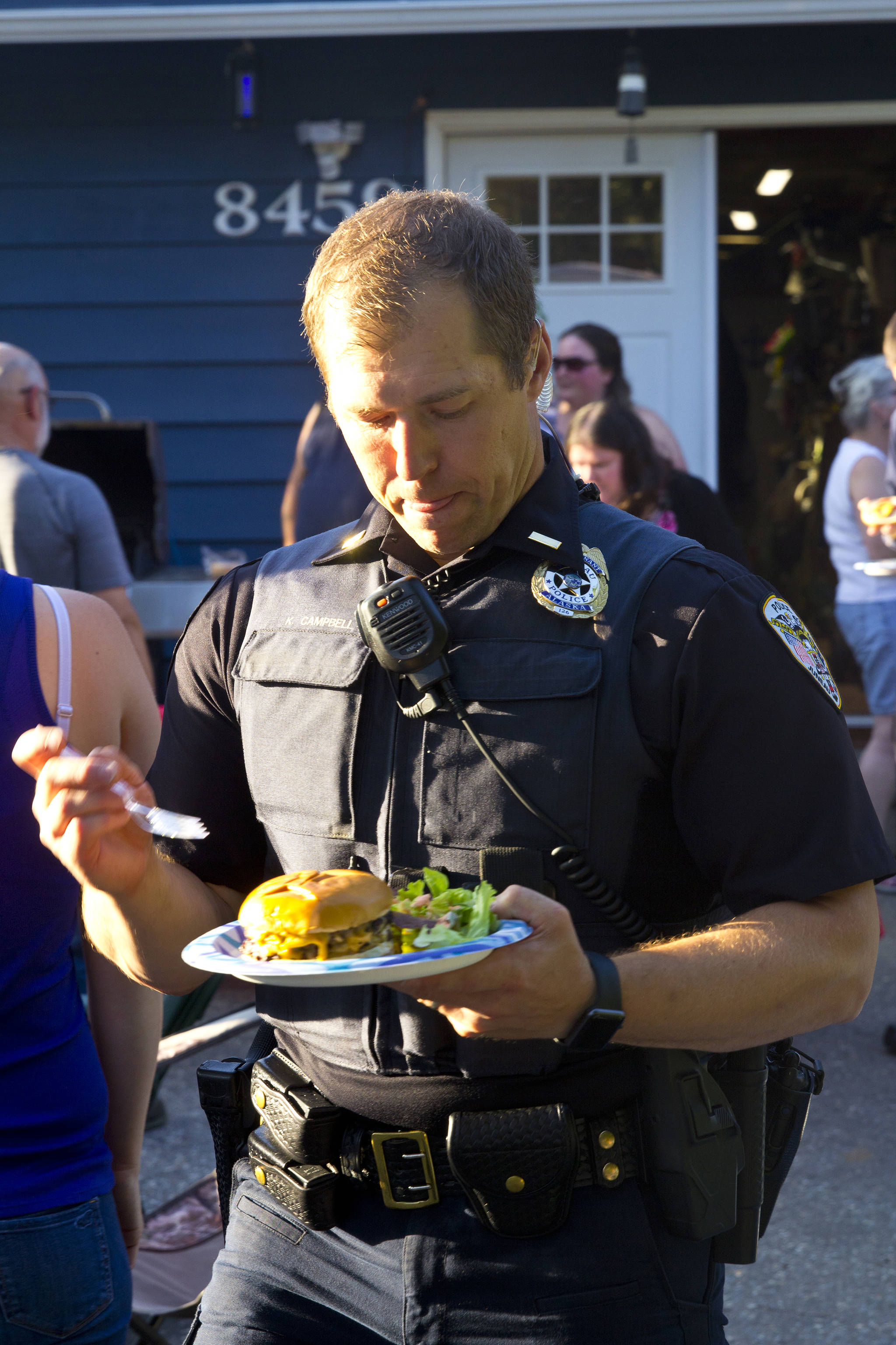 Lt. Krag Campbell, patrol lieutenant with the Juneau Police Department, enjoys a bite to eat at a party during the National Night Out, Aug. 6, 2019. (Michael S. Lockett | Juneau Empire)