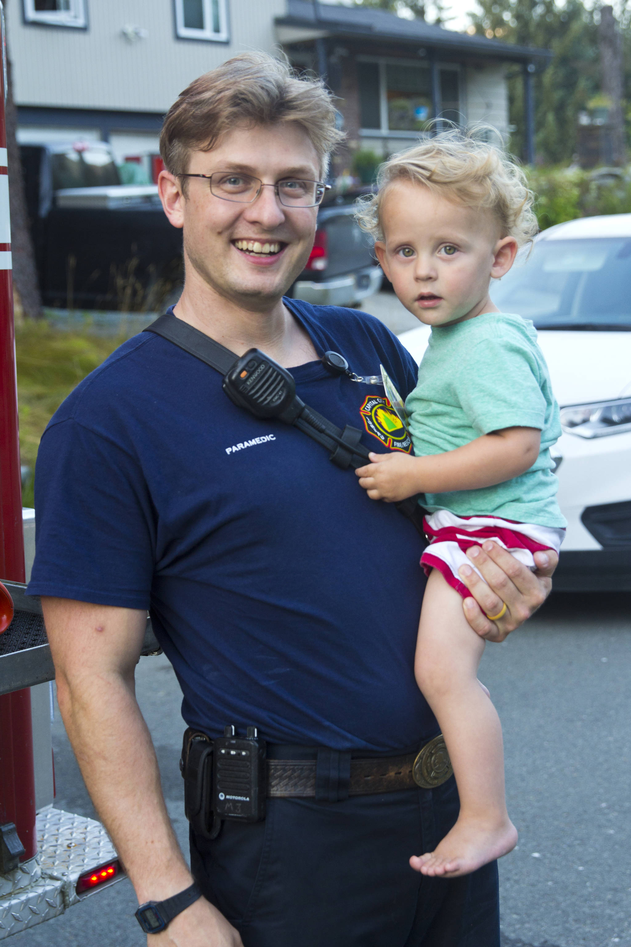 Travis Larsen, paramedic with Capital City Fire/Rescue, poses with his child during National Night Out, Aug. 6, 2019. (Michael S. Lockett | Juneau Empire)