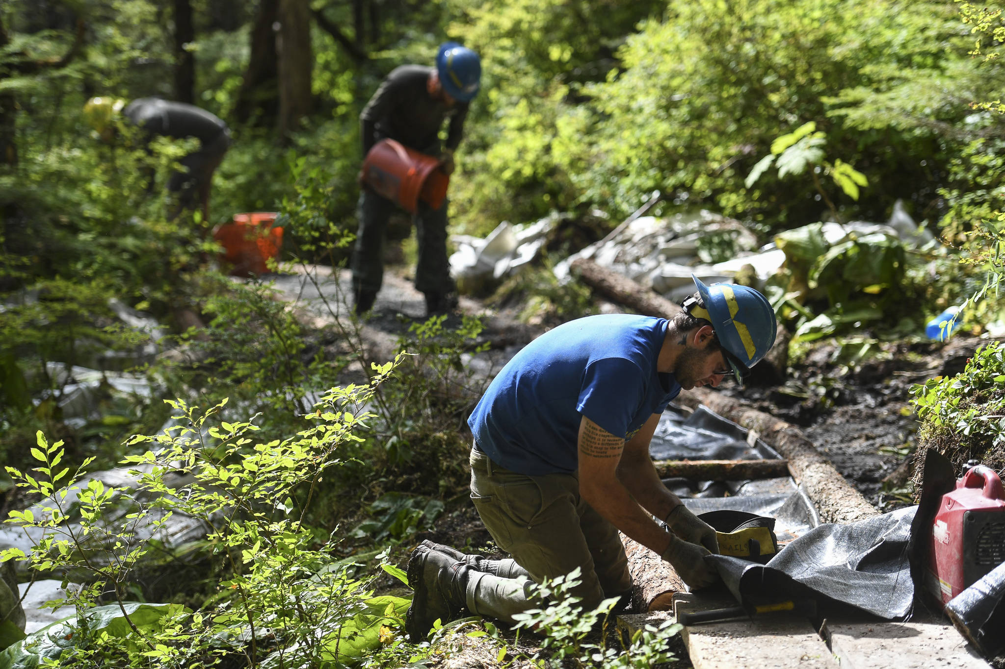 Andres Velez, right, Jase Tweedy, center, and Lou Eney work on the Auke Nu Trail splits on the way to the John Muir Cabin on Wednesday, Aug. 7, 2019. (Michael Penn | Juneau Empire)