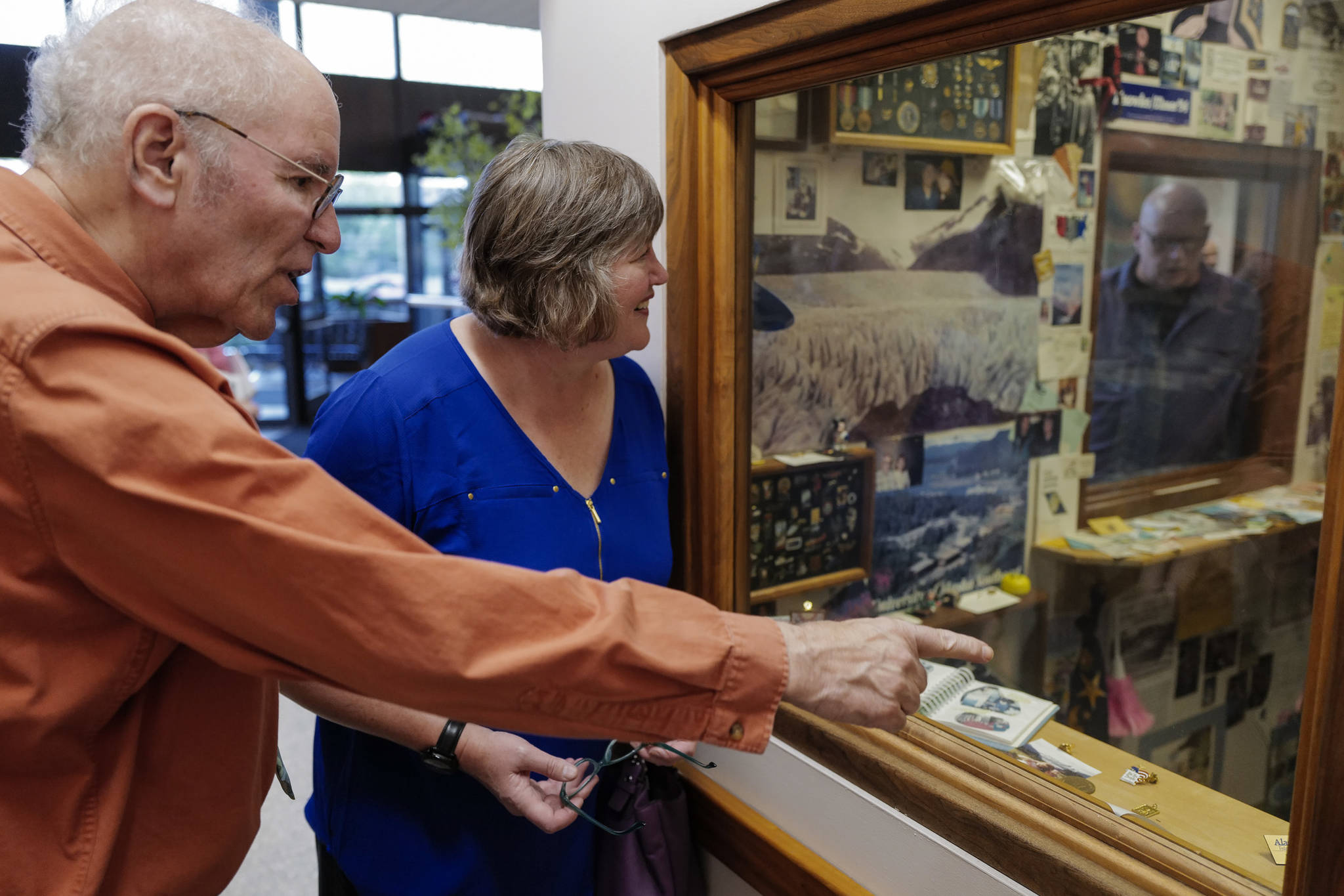 Michael Orelove, left, talks with Rep. Sara Hannan, D-Juneau, as they look at items on the 25th anniversary of the 1994 Juneau Time Capsule at the Hurff Ackerman Saunders Federal Building in Juneau on Friday, Aug. 9, 2019. Mark Farmer, right, looks in through a second window. Ovelove was on the committee that set up the capsule which is set to be opened at the 100 year mark. (Michael Penn | Juneau Empire)