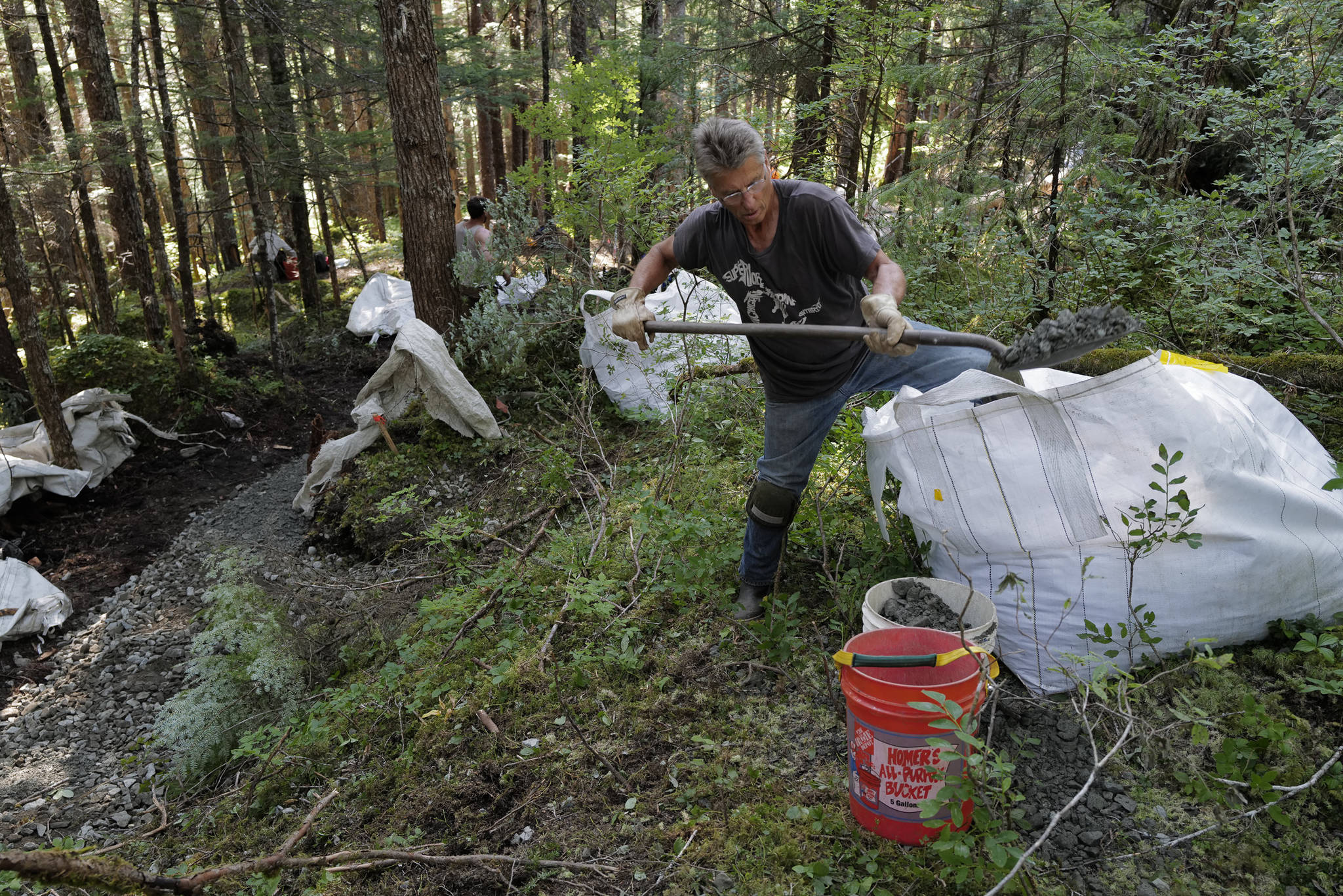 Volunteer Dave Haas shovels gravel for a new Treadwell Gorge reroute trail on the Treadwell Ditch Trail on Thursday, Aug. 8, 2019. (Michael Penn | Juneau Empire)