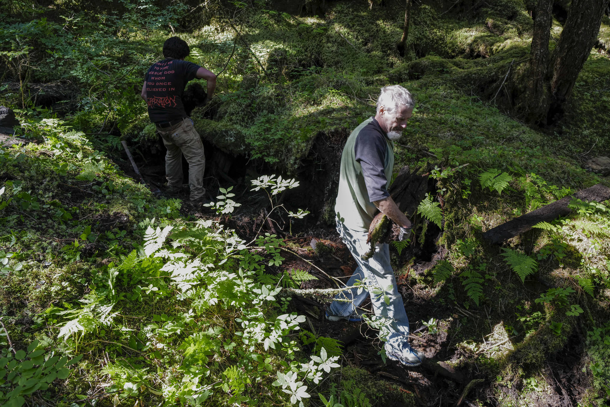 Diego Noboa, of Trail Mix, left, and volunteer Craig Good clear an area of debris for a drainage pipe on a new Treadwell Gorge reroute trail on the Treadwell Ditch Trail on Thursday, Aug. 8, 2019. (Michael Penn | Juneau Empire)