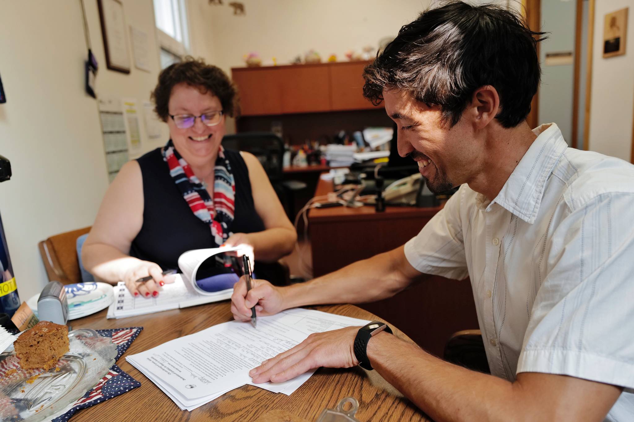 Greg Smith signs his application in front of Municipal Clerk Beth McEwen on Monday, Aug. 12, 2019, to run for one of two Assembly District 1 seats in this falls municipal election. (Michael Penn | Juneau Empire)