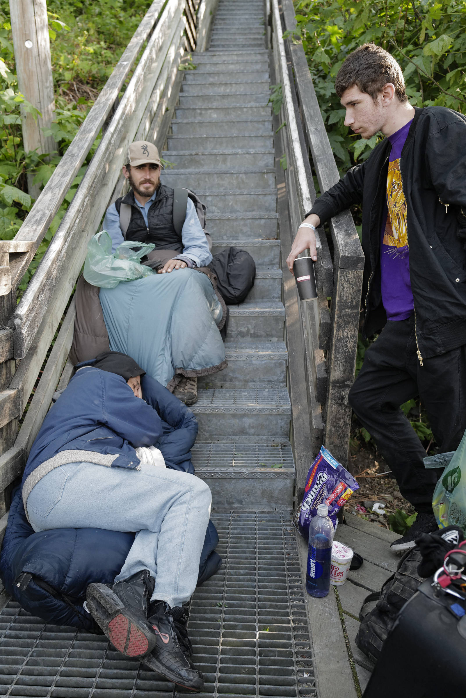 Homeless people spend their time on the Decker Way stairs after the Glory Hall’s closure on Tuesday, Aug. 13, 2019. (Michael Penn | Juneau Empire)