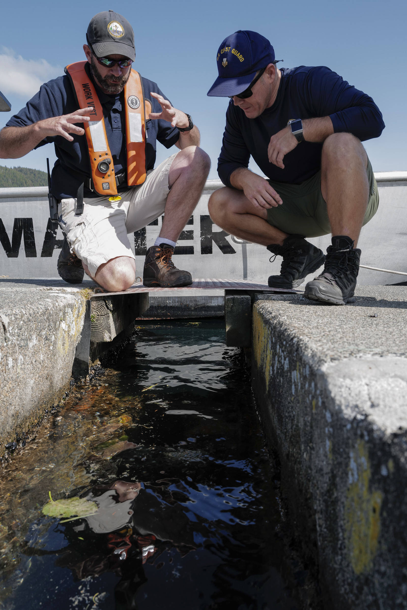 Deputy Harbormaster Matt Creswell, left, explains to the project to Shawn Price, of U.S. Coast Guard Regional Dive Locker West, at the Don D. Statter Boat Harbor in Auke Bay on Friday, Aug. 16, 2019. Members of the U.S. Army’s 74th Engineer Dive Detachment and U.S. Coast Guard Regional Dive Locker West worked together to inspect and replace the bolts holding the harbor’s breakwater together. (Michael Penn | Juneau Empire)