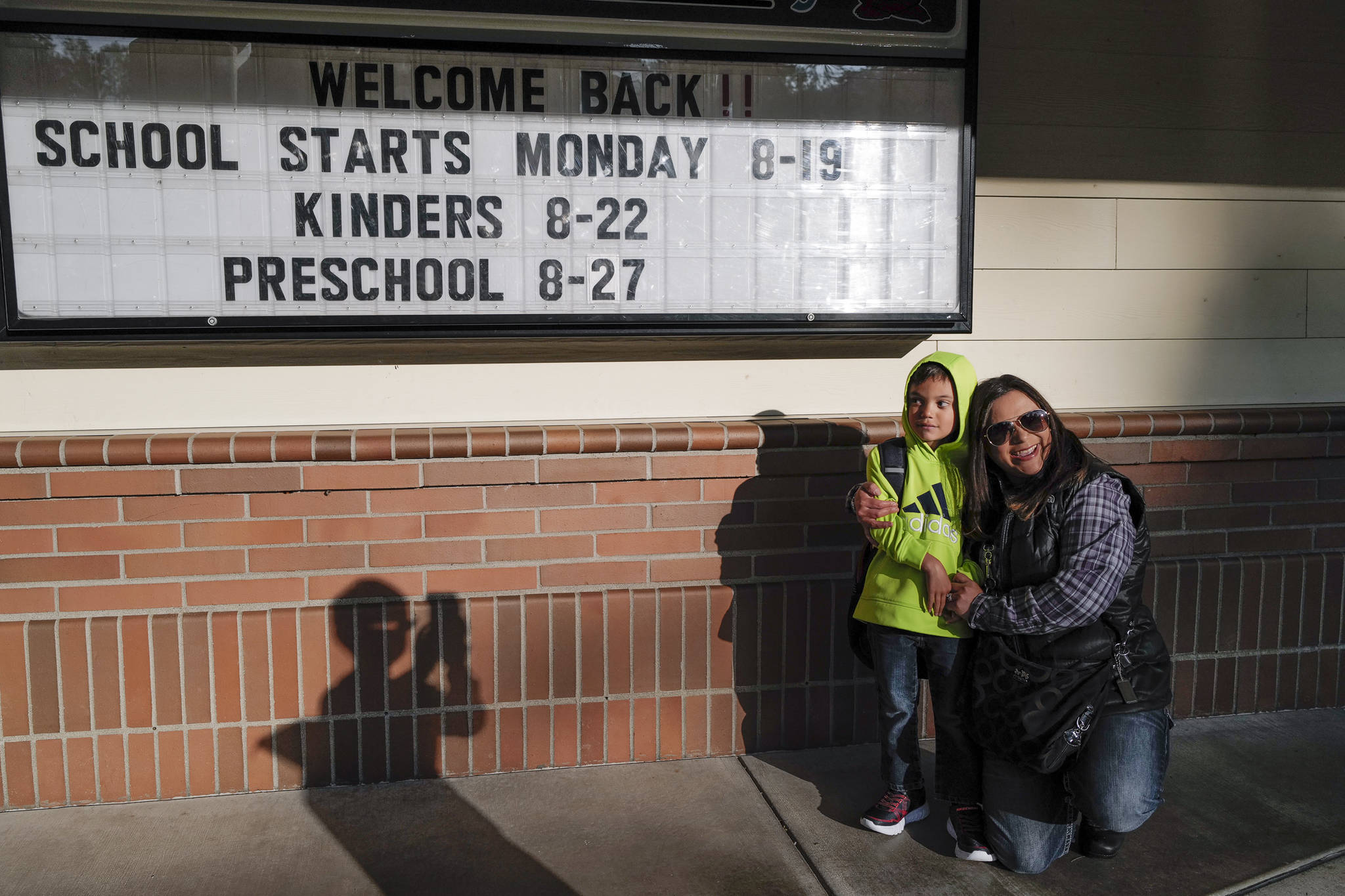Fifth-grader Gage Keller, takes a picture of his brother Gary arriving for second grade with their mother, Lisa, on the first day of school at Riverbend Elementary School on Monday, Aug. 19, 2019. (Michael Penn | Juneau Empire)
