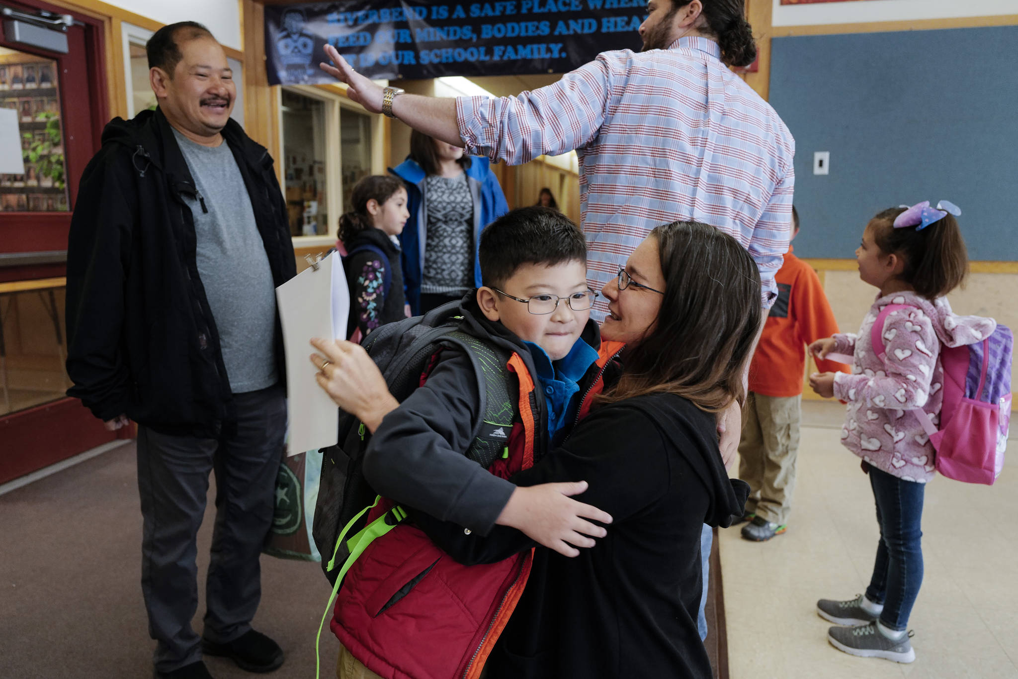 Nghiem Tran, left, watches as his son, William, arrives for second grade and is greeted by Music Teacher Rebecca Ricker on the first day of school at Riverbend Elementary School on Monday, Aug. 19, 2019. (Michael Penn | Juneau Empire)