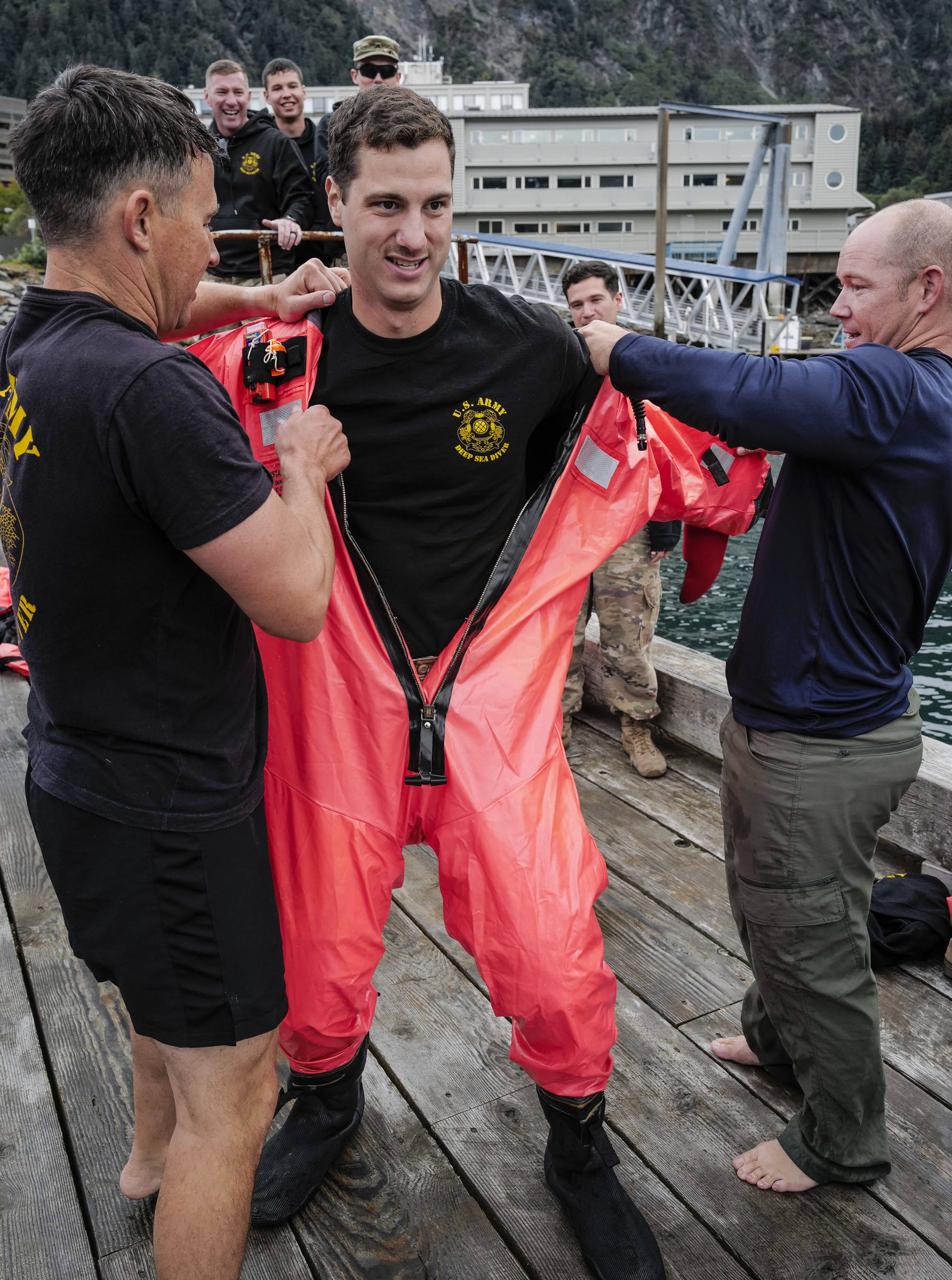Brett Hyde, of the U.S. Army Dive Team, center, is helped into his survival suit by teammates Daniel Byrd, left, and Shawn Price during the annual Buoy Tender Olympics at Station Juneau on Wednesday, Aug. 21, 2019. (Michael Penn | Juneau Empire)