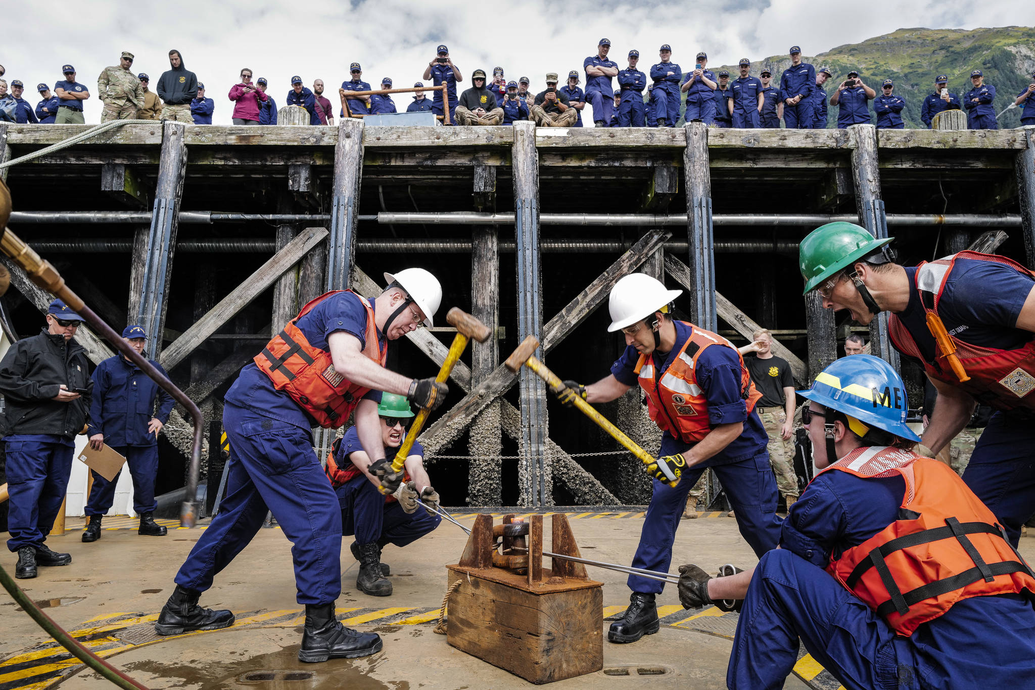 Members of the U.S. Coast Guard Cutter Kukui participate in the “heat and beat” contest during the annual Buoy Tender Olympics at Station Juneau on Wednesday, Aug. 21, 2019. Lt. Cdr. Ray Reichl, left, swings a sledge hammer with Lt. Cyrus Unvala as teammates Ens. Joseph Snyder and Ens. Victoria Sparacino hold the shackle and Enx. Reid Wiegleb yells encouragement. (Michael Penn | Juneau Empire)