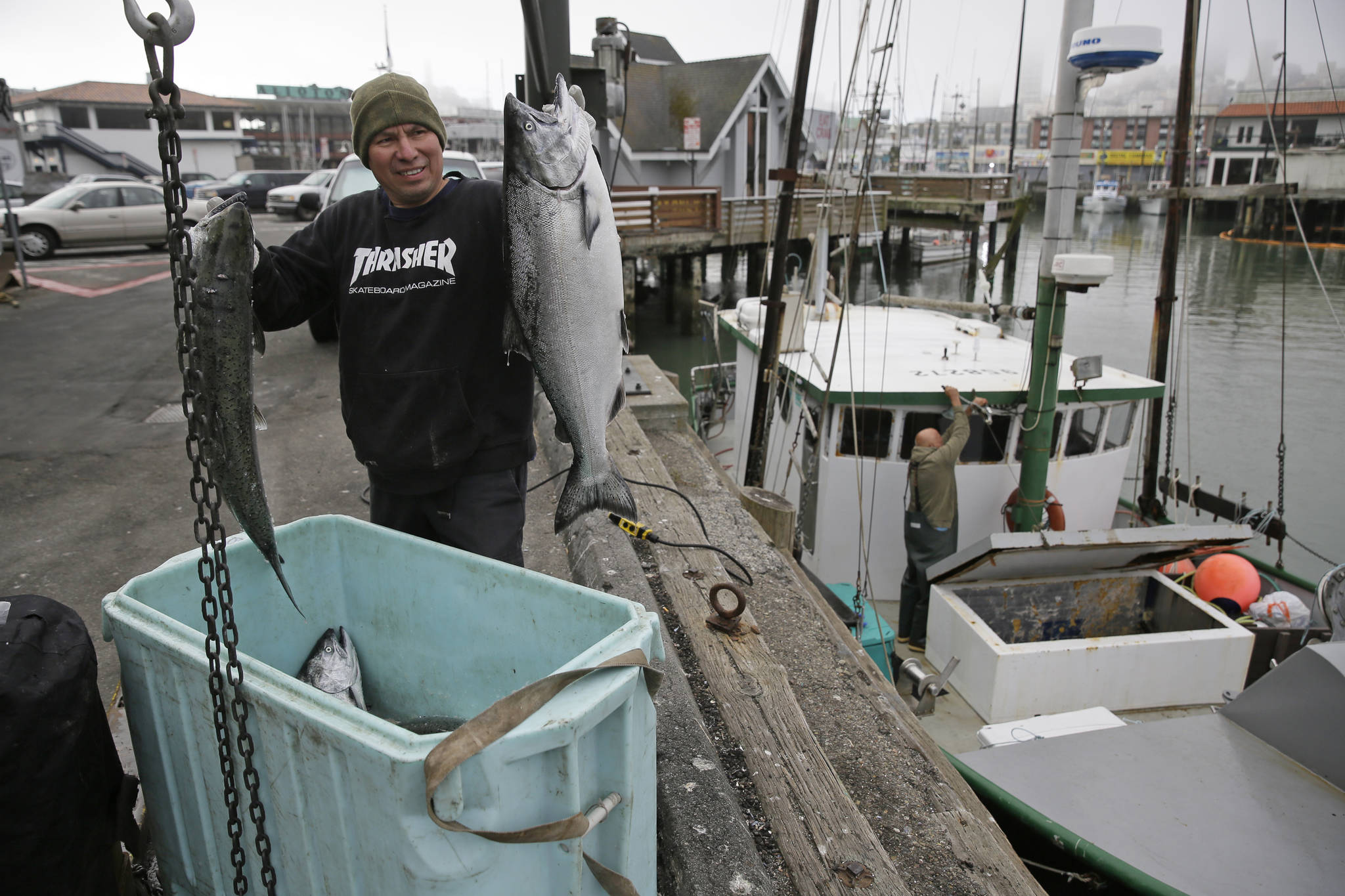 In this photo taken Monday, July 22, 2019, Ivan Montoya, left, of Flannery Seafood, holds up chinook salmon after it was brought in by Ron Kemp, right, at Fisherman’s Wharf in San Francisco. California fishermen are reporting one of the best salmon fishing seasons in more than a decade, thanks to heavy rain and snow that ended the state’s historic drought. It’s a sharp reversal for chinook salmon, also known as king salmon, an iconic fish that helps sustain many Pacific Coast fishing communities.(AP Photo/Eric Risberg)