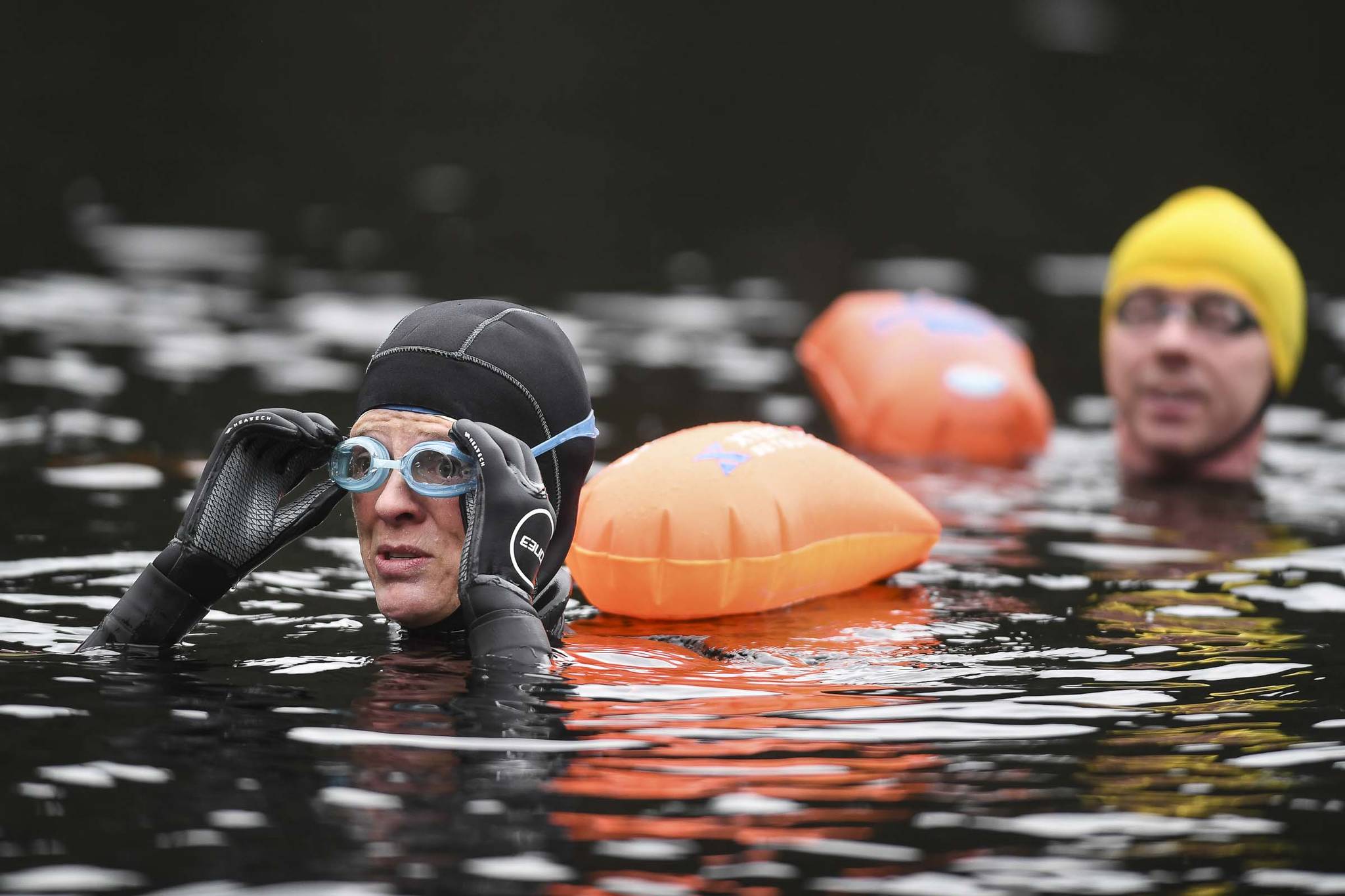 Amy Carroll adjusts her goggles while training with other swimmers in Auke Lake on Wednesday, June 5, 2019. (Michael Penn | Juneau Empire)