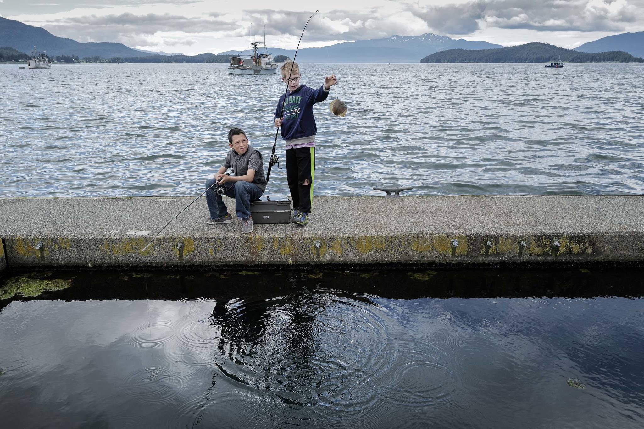 Scott Newman, 10, watches Steel Morgan, 10, pull out a small flounder at the Don D. Statter Memorial Boat Harbor in Auke Bay, on Monday, June 24, 2019. (Michael Penn | Juneau Empire)