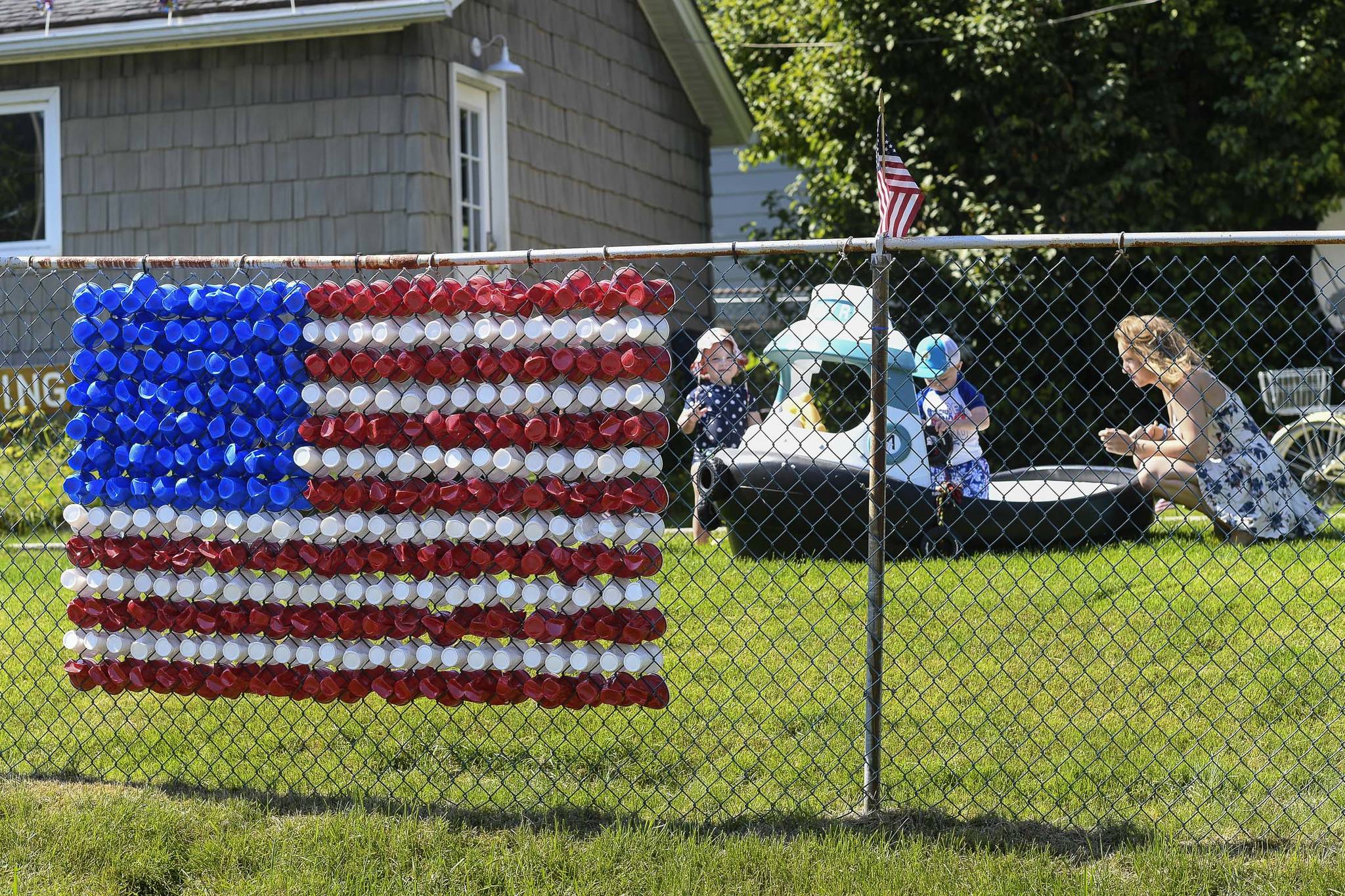 Caila McCoy watches as Presley and Jimmy play in a toy boat on 2nd Street in Douglas on Thursday, June 27, 2019. The home is one of a number of yards and business that decorate for the Fourth of July. (Michael Penn | Juneau Empire)