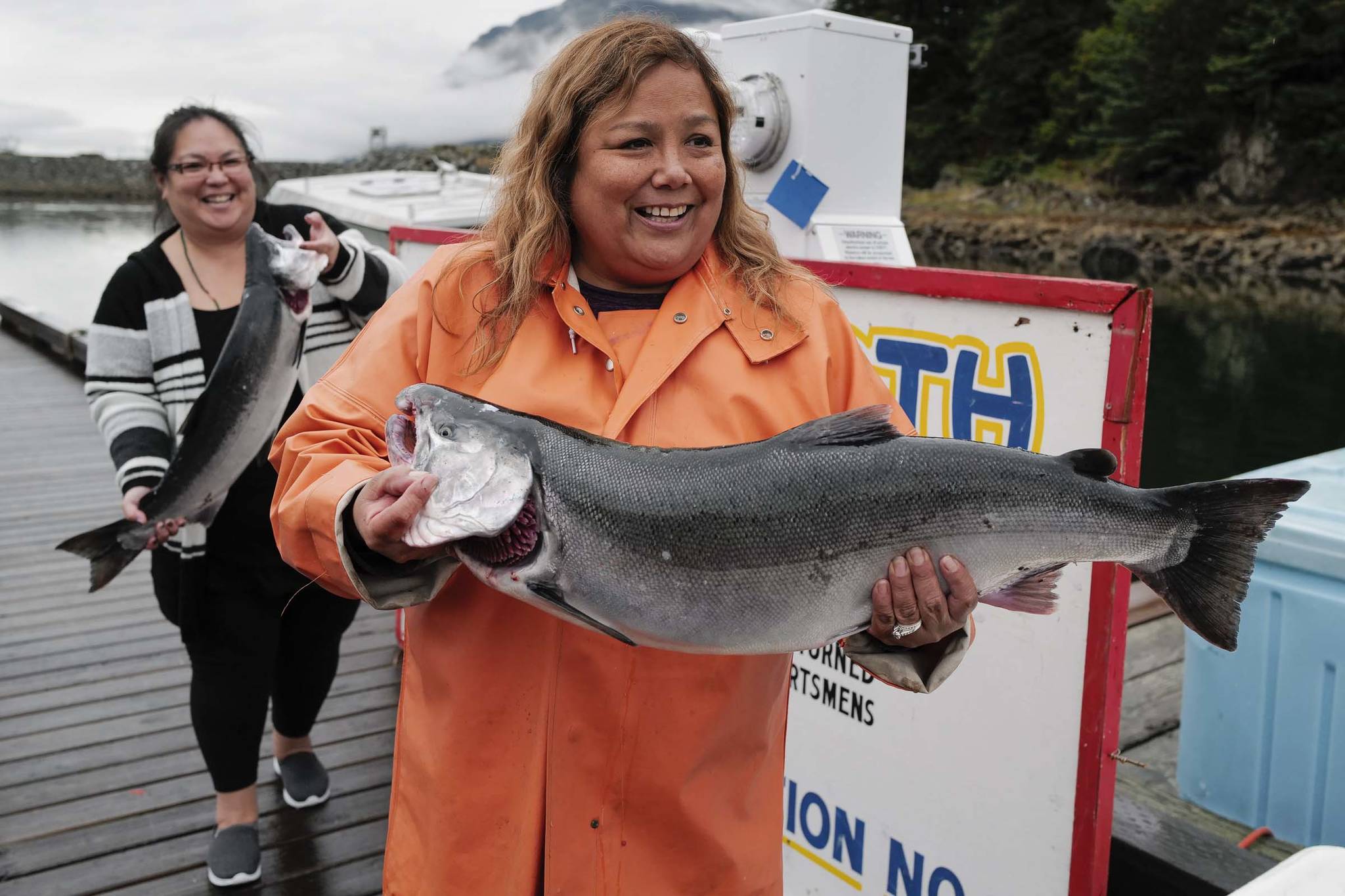 Anilisa Kimlinger, right, and Anna Marie Eldemar carry their cohos to the Golden North Salmon Derby weigh-in station at the Mike Pusich Douglas Harbor on Friday, Aug. 23, 2019. Kimlinger’s coho weighed in at 15.8 pounds. (Michael Penn | Juneau Empire)