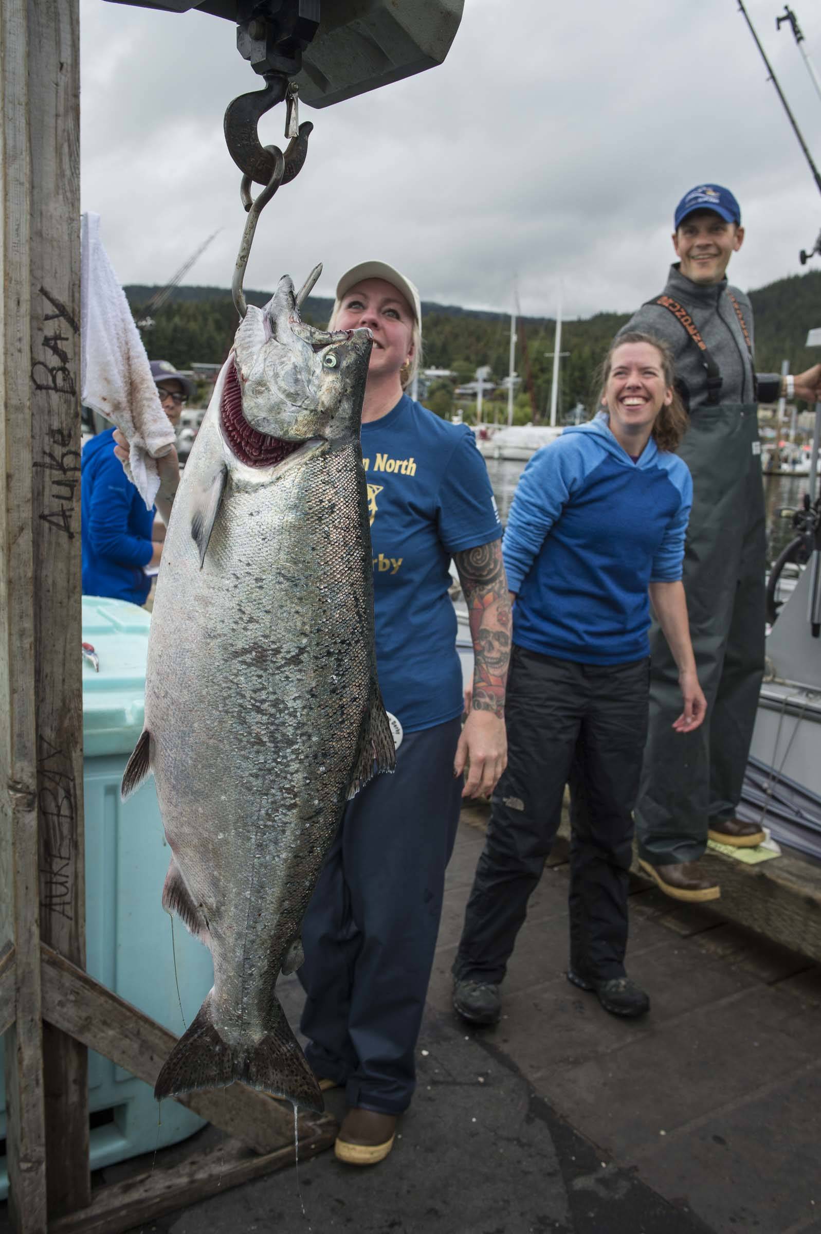 Sadie Wright, center, and Chris Krenz, right, watch as volunteer Kami Bartness weights Wright’s king salmon at the Golden North Salmon Derby’s station at the Don D. Statter Memorial Boat Harbor on Saturday, Aug. 24, 2019. The fish weighted in at 20.1 pounds. (Michael Penn | Juneau Empire)