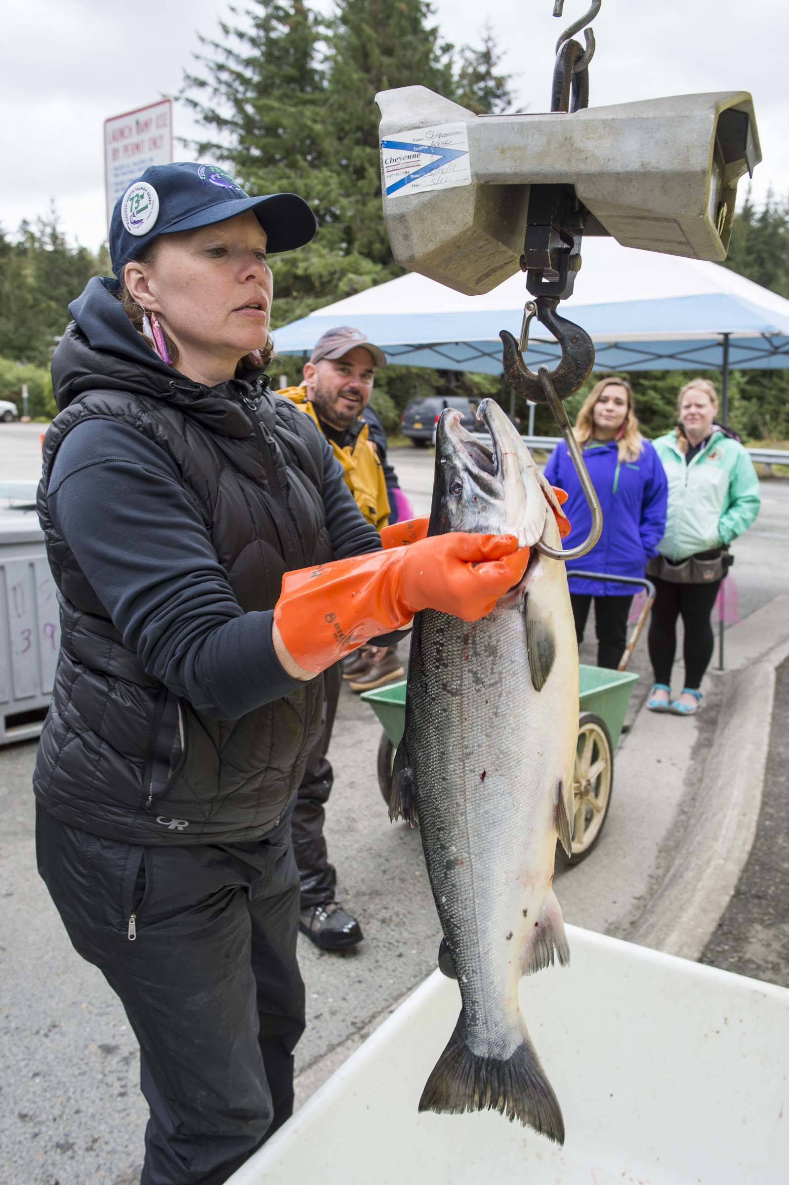 Volunteer Misty Smith weighs a coho turned in by John Bohan at the Golden North Salmon Derby’s station at Amalga Harbor on Saturday, Aug. 24, 2019. (Michael Penn | Juneau Empire)