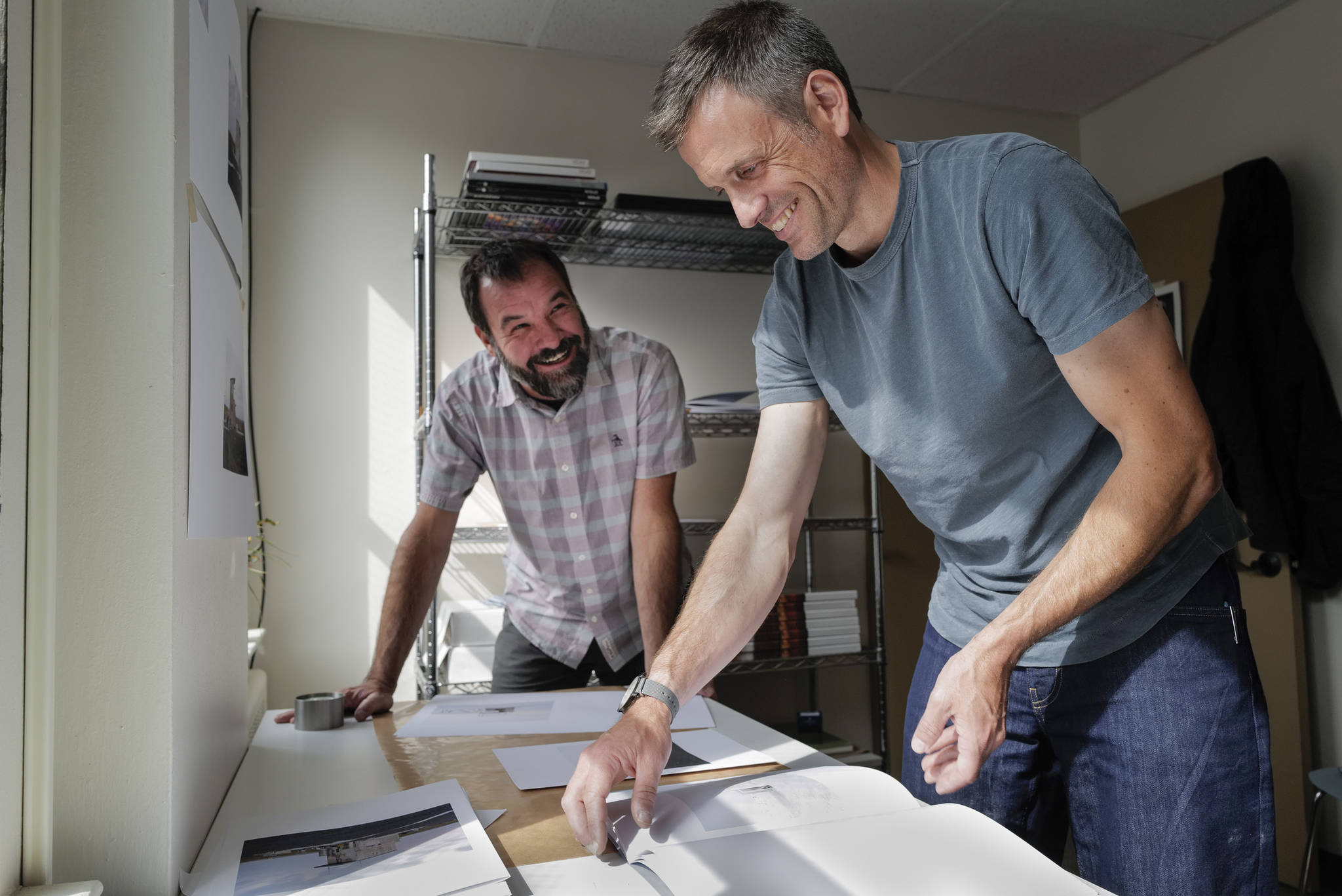 Seattle-based photographer Eirik Johnson, left, works with Ben Huff, a local photographer and editor of Ice Fog Press, on a hand-made book of Johnson’s photographs titled “Barrow Cabins” on Wednesday, Aug. 21, 2019. (Michael Penn | Juneau Empire)