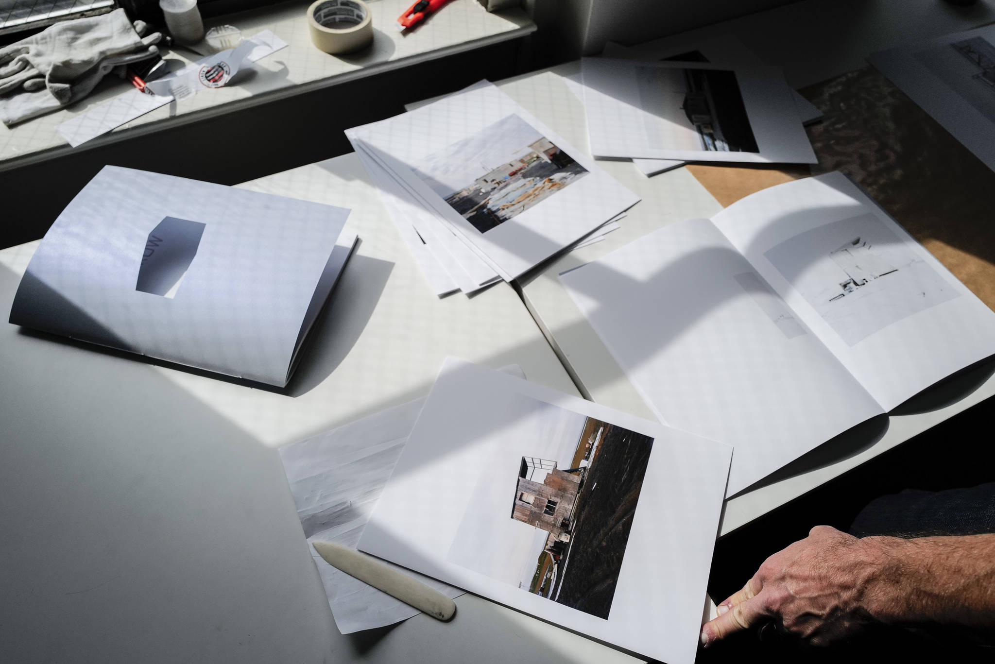 Seattle-based photographer Eirik Johnson works with Ben Huff, a local photographer and editor of Ice Fog Press, on a hand-made book of Johnson’s photographs titled “Barrow Cabins” on Wednesday, Aug. 21, 2019. (Michael Penn | Juneau Empire)