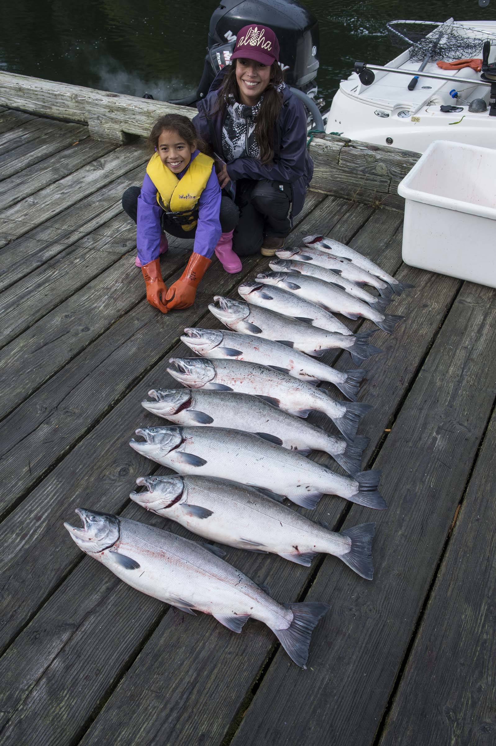 Marie Taug and her daughter, Zoe Tagsip, 9, pose with a dozen coho brought in by their boat to the Mike Pusich Douglas Boat Harbor during the Golden North Salmon Derby on Saturday. (Michael Penn | Juneau Empire)