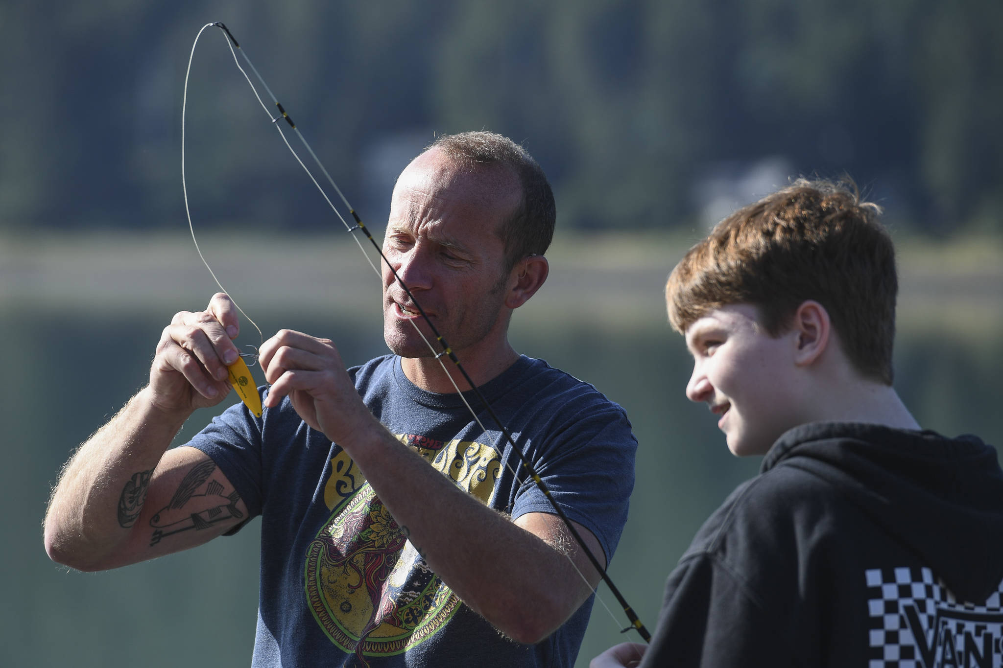 Dzantik’i Heeni Middle School eighth-grader Riley Kellar, right, is helped by Teacher Bobby Jones while fishing for salmon at the Wayside Park on Channel Drive on Friday, Aug. 30, 2019. The fish will be used in a dog treat business the students are developing to raise money for a water filtering system to be used at the school. Two math teachers, Jones and Tennie Bentz, are having the students start four businesses as a way of teaching the use of math in the real world. (Michael Penn | Juneau Empire)