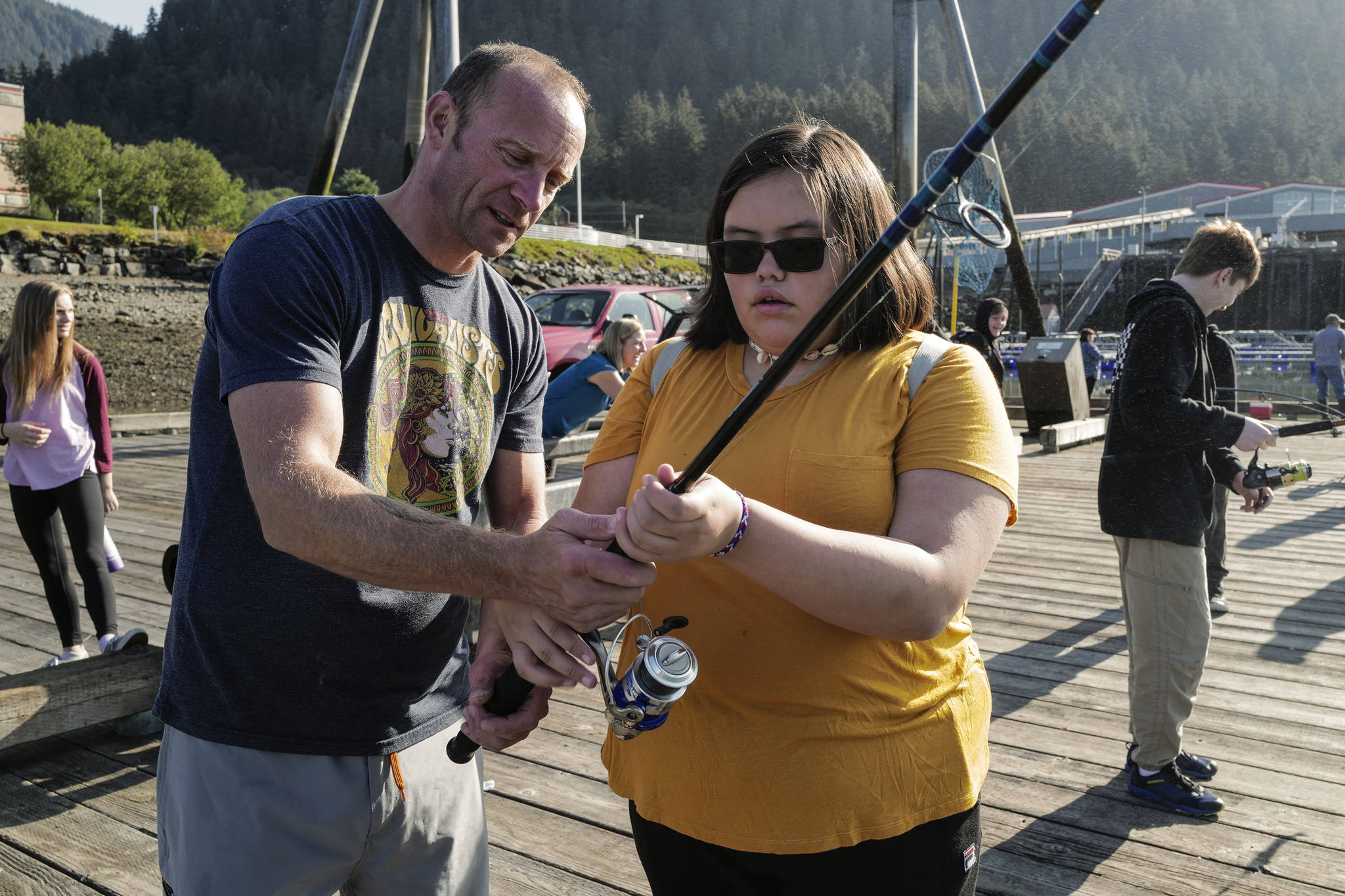 Dzantak’i Heeni Middle School eighth-grader Jaylynn Martin, right, is helped by Teacher Bobby Jones while fishing for salmon at the Wayside Park on Channel Drive on Friday, Aug. 30, 2019. The fish will be used in a dog treat business the students are developing to raise money for a water filtering system to be used at the school. Two math teachers, Jones and Tennie Bentz, are having the students start four businesses as a way of teaching the use of math in the real world. (Michael Penn | Juneau Empire)
