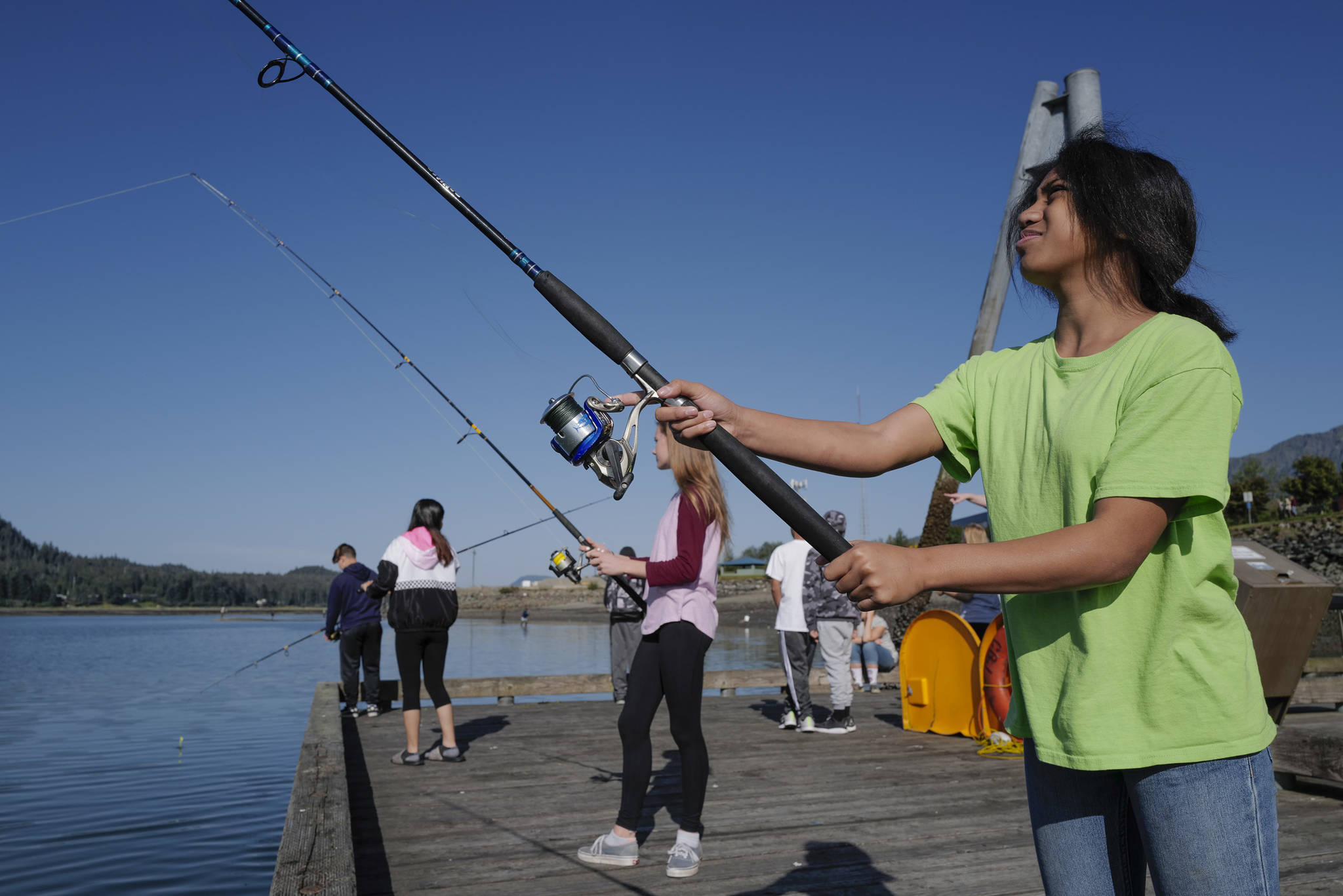 Dzantik’i Heeni Middle School eighth-grader Pua Ahhney, right, and Elizabeth Eriksen fish for salmon at the Wayside Park on Channel Drive on Friday, Aug. 30, 2019. The fish will be used in a dog treat business the students are developing to raise money for a water filtering system to be used at the school. Two math teachers, Jones and Tennie Bentz, are having the students start four businesses as a way of teaching the use of math in the real world. (Michael Penn | Juneau Empire)