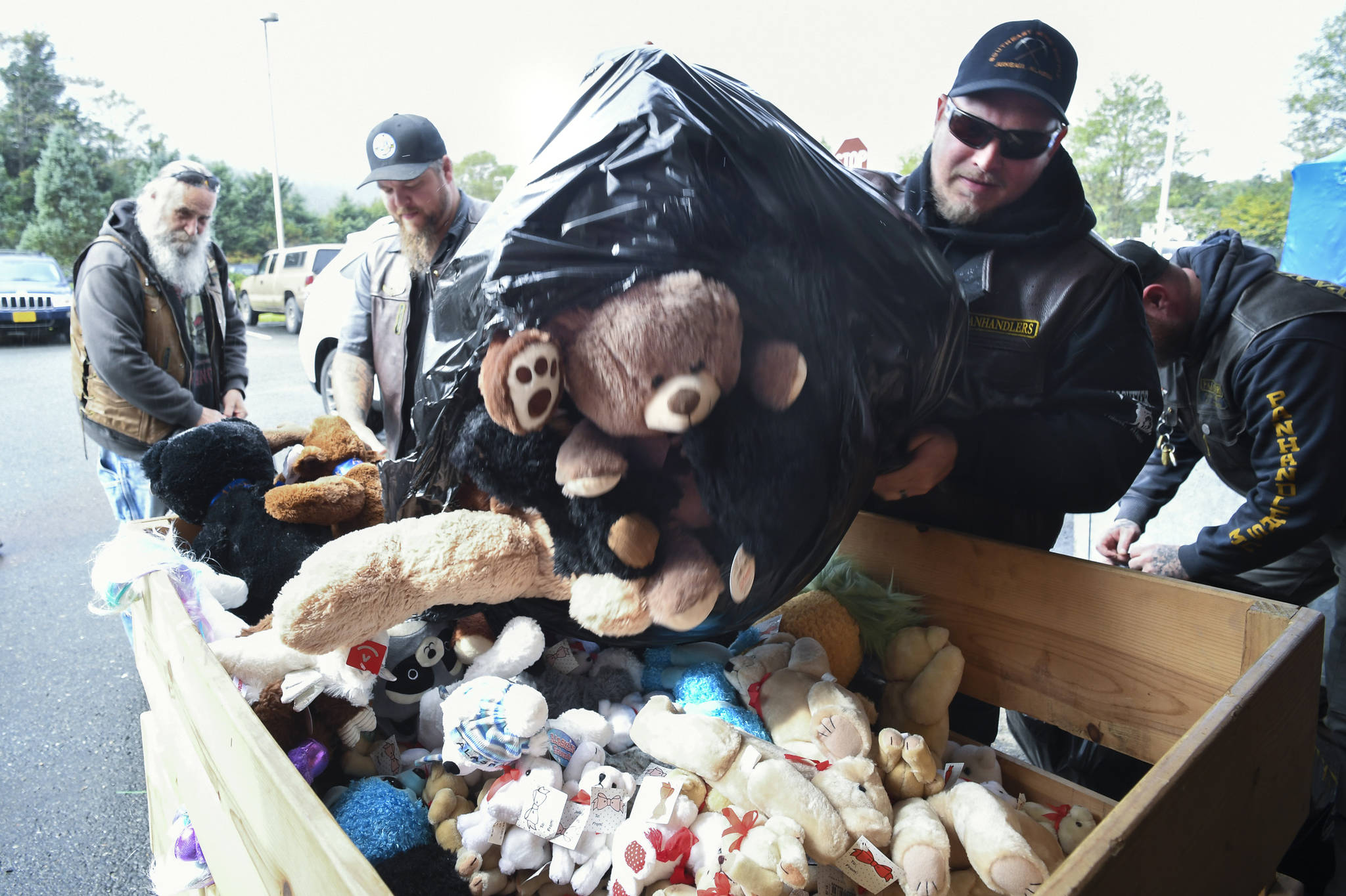 Joe Bingham, right, unloads a bag of stuffed toys with other members of the Panhandlers Motorcycle Club of Alaska at Bartlett Regional Hospital on Tuesday. The toys were collected during the 25th Annual Toy Run for young patients and visitors to the hospital.                                <strong>Michael Penn</strong> | Juneau Empire