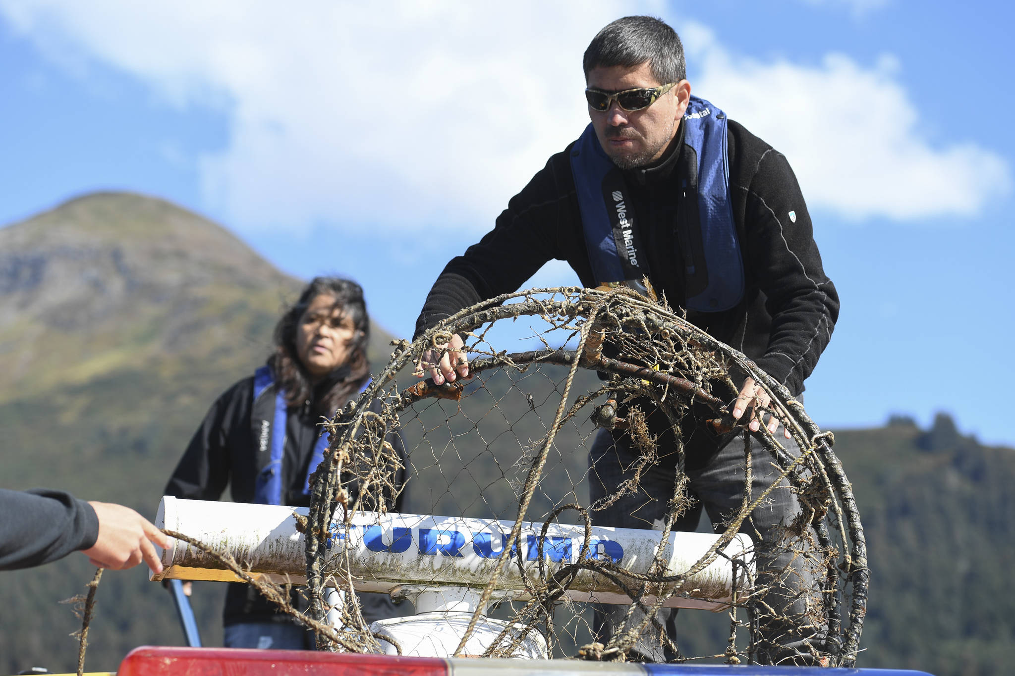 Kamal Lindoff, right, and Bernadine DeAsis store an old crab pot as members of the Army’s 74th Engineer Dive Detachment work off a Juneau Harbormaster boat to retrieve lost crab pots in Gastineau Channel for the Douglas Indian Association/NOAA Marine Debris Project on Thursday, Sept. 5, 2019. The project aims to identify and remove derelict crab pots and their continued negative impact on wildlife and the environment. (Michael Penn | Juneau Empire)