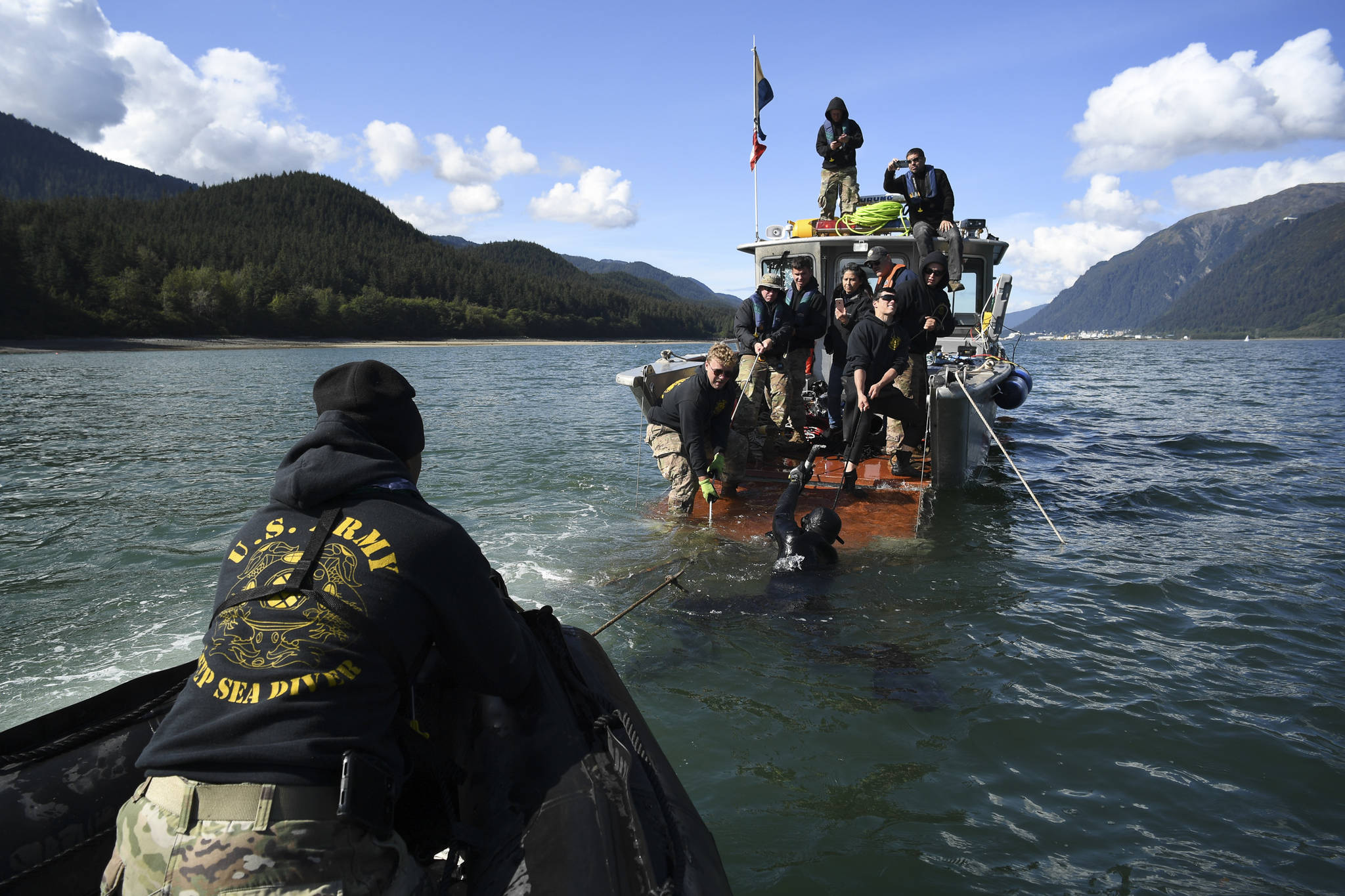 Members of the Army’s 74th Engineer Dive Detachment work off a Juneau Harbormaster boat to pull up a lost commercial crab pot in Gastineau Channel for the Douglas Indian Association/NOAA Marine Debris Project on Thursday, Sept. 5, 2019. The project aims to identify and remove derelict crab pots and their continued negative impact on wildlife and the environment. (Michael Penn | Juneau Empire)