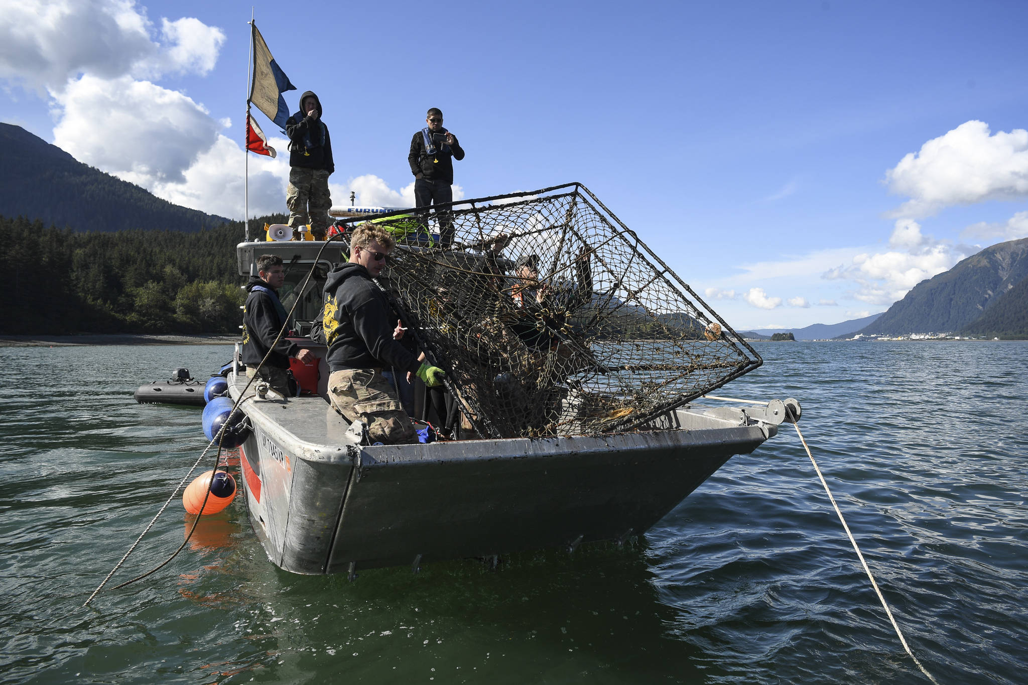 Members of the Army’s 74th Engineer Dive Detachment work off a Juneau Harbormaster boat to pull up a lost commercial crab pot in Gastineau Channel for the Douglas Indian Association/NOAA Marine Debris Project on Thursday, Sept. 5, 2019. The project aims to identify and remove derelict crab pots and their continued negative impact on wildlife and the environment. (Michael Penn | Juneau Empire)