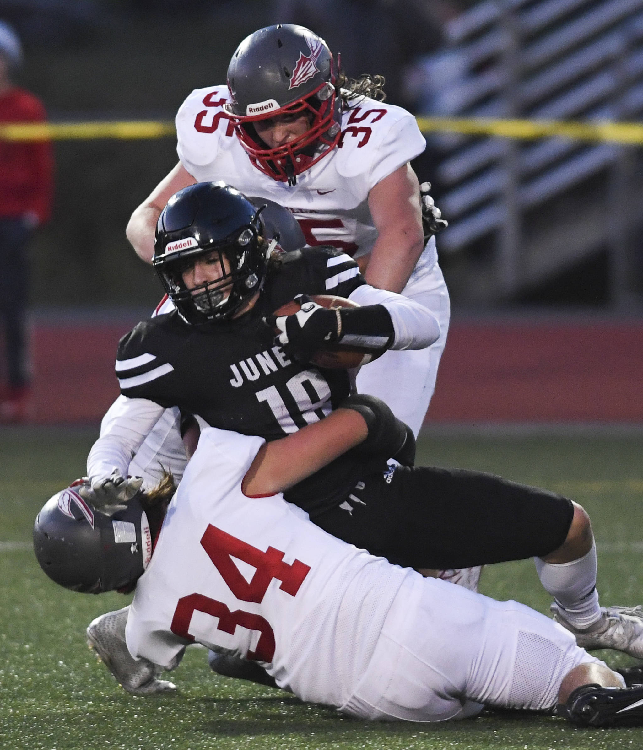 Juneau’s Cooper Kriegmont is brought down by Wasilla’s Sawyer Drumm, bottom, and Tristan Wake in the second quarter at Adair-Kennedy Memorial Field on Friday, Sept. 6, 2019. Juneau won 63-0. (Michael Penn | Juneau Empire)