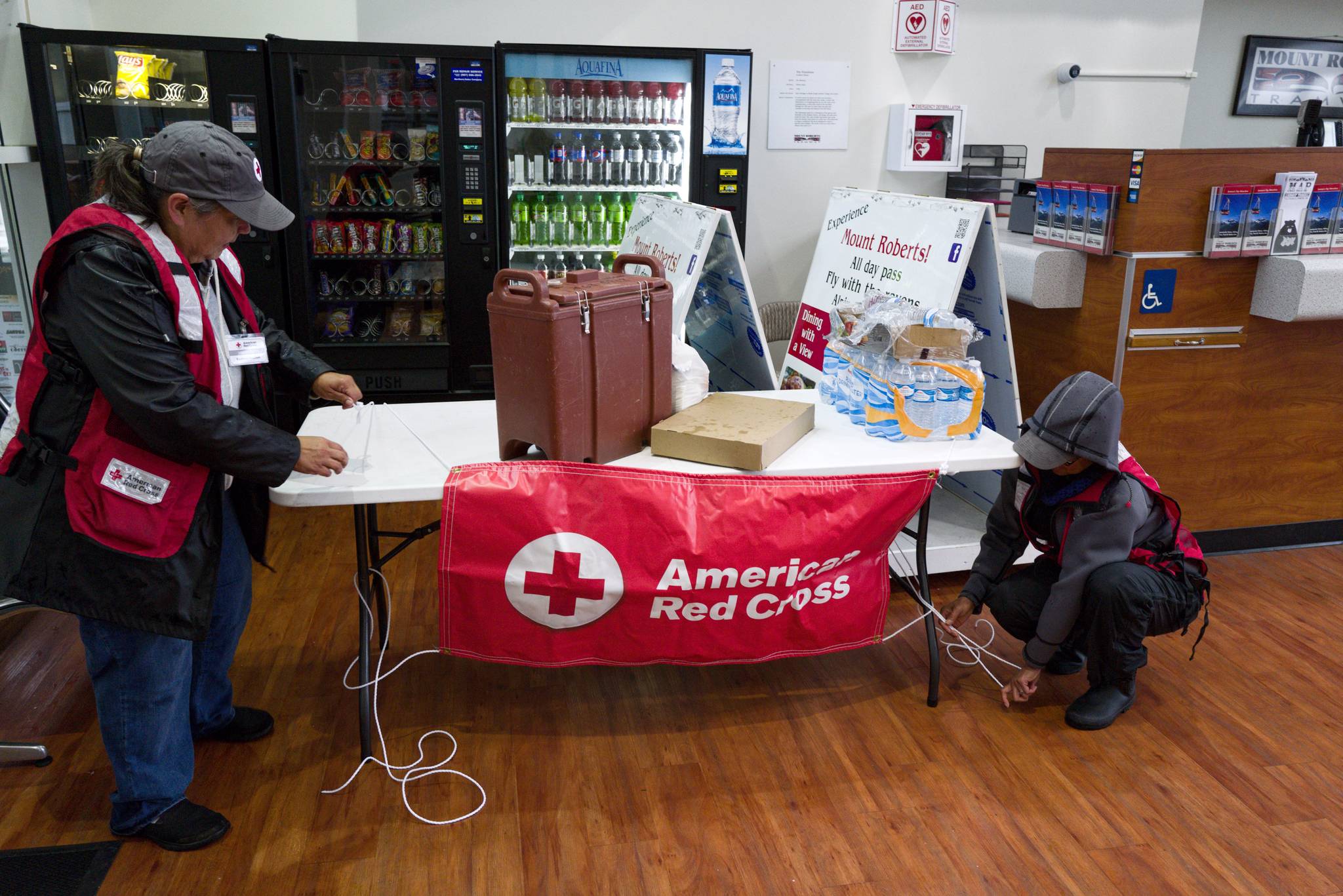 Ralphenia Knudson, left, and Carolyn Garcia, of the American Red Cross, set up a table at the Mount Roberts Tramway as rescuers gather to find a lost hiker on Mount Roberts on Friday, Sept. 20, 2019. (Michael Penn | Juneau Empire)