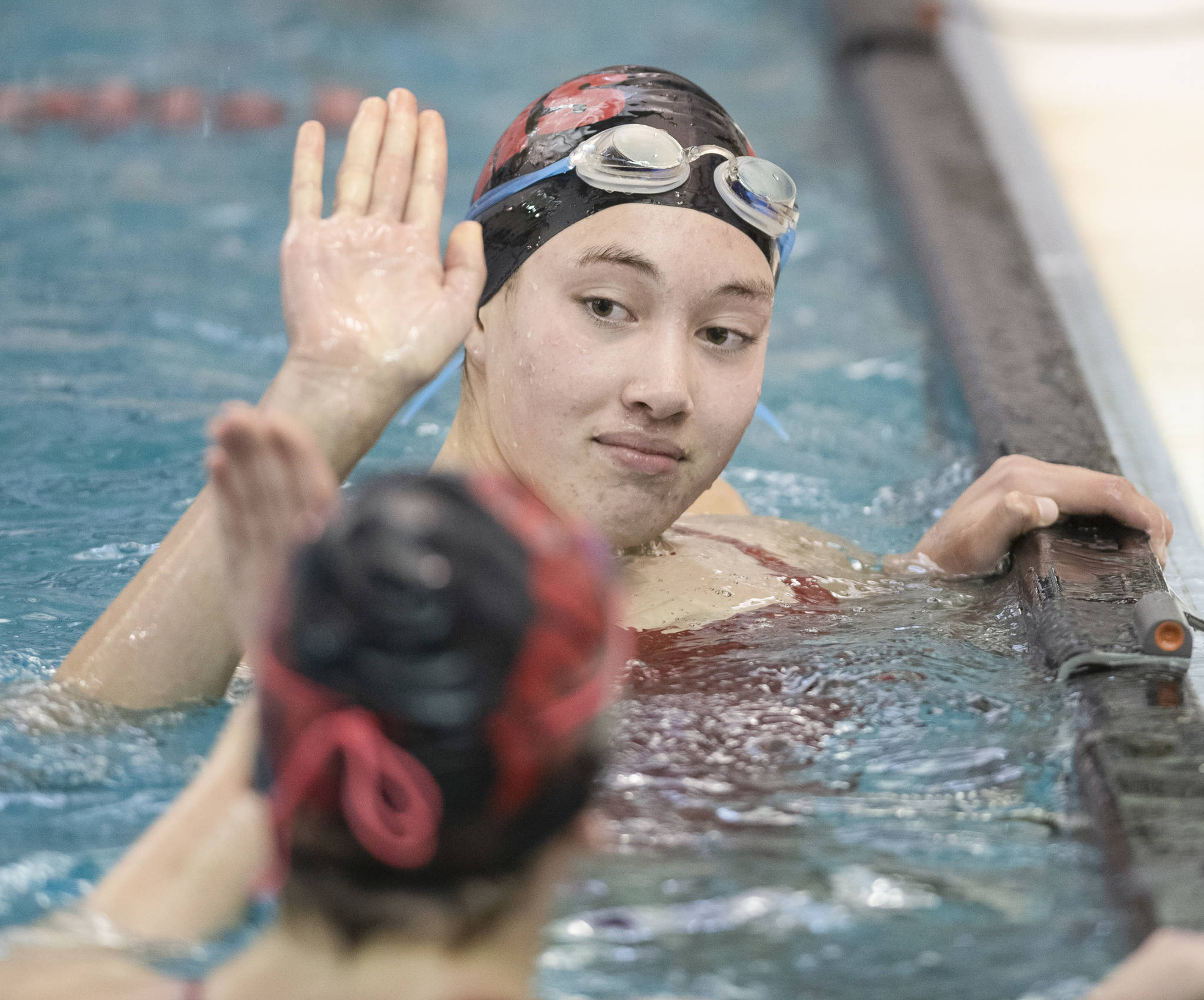 Juneau-Douglas’ Addy Mallot, top, gives a high-five to teammate Mesa Moran after competing in the 50 Yard Freestyle at the Juneau Invitational Swim Meet at the Dimond Park Aquatic Center on Friday, Sept. 20, 2019. (Michael Penn | Juneau Empire)