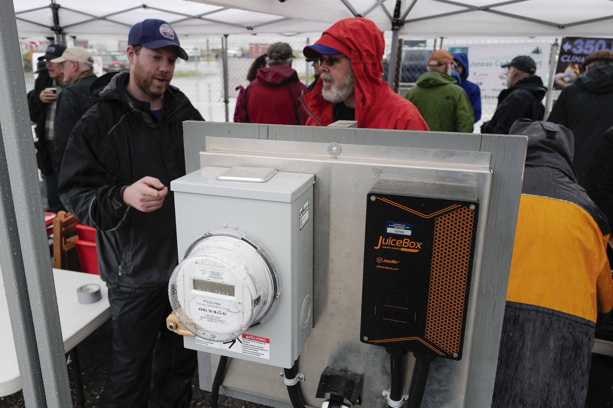 Alec Mesdag, of AEL&P, left, talks to Sean Edwards about their reduced rates and portable charging station for electric vehicles as Juneau residents meet for the 6th Annual Electric Vehicle Juneau Roundup on Saturday, Sept. 21, 2019. (Michael Penn | Juneau Empire)