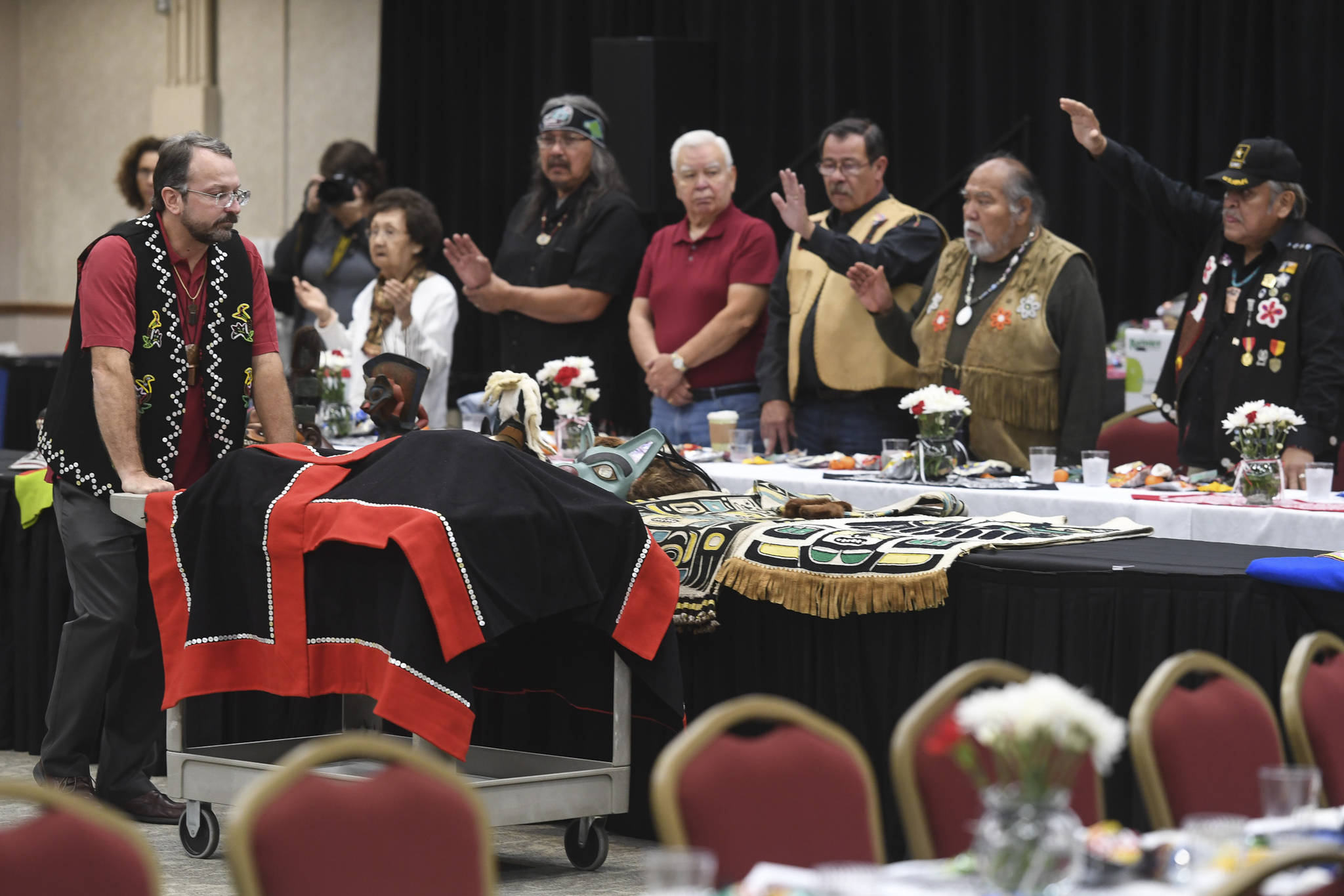 Eric Hollinger, Tribal Liaison for the Repatriation Office of the Smithsonian’s National Museum of Natural History, left, pushes in a cart holding the original sculpin clan hat for a welcoming ceremony at Elizabeth Peratrovich Hall on Wednesday, Sept. 25, 2019. The hat was collected from the Kiks.ádi Clan in Sitka in 1884. The Smithsonian Institution used a 3D digitization process to document the hat and constructed a replica hat using traditional materials. (Michael Penn | Juneau Empire)