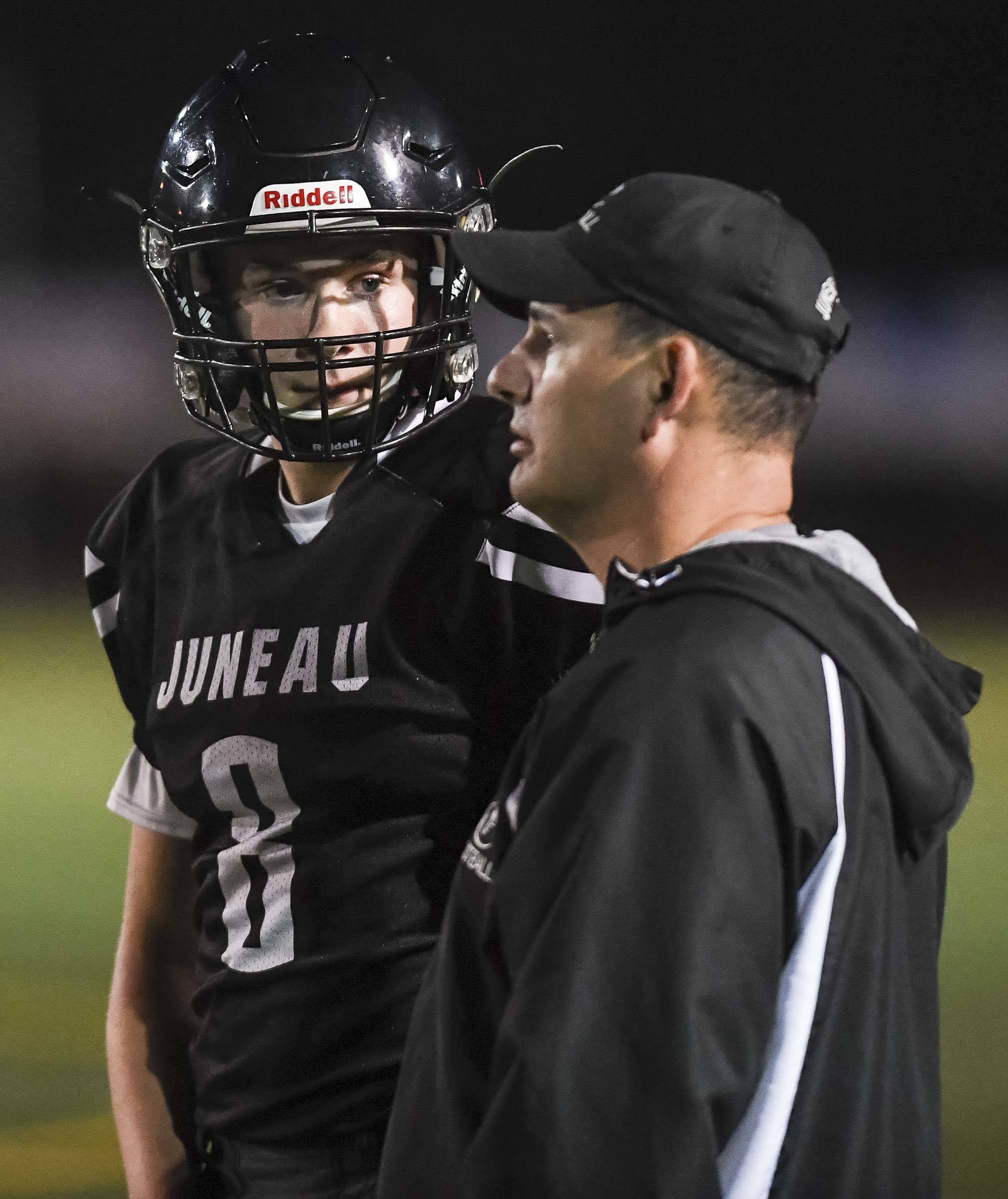 Juneau’s Noah Chambers receives a play by coach Rich Sjoroos as they play against Antelope Union in the third quarter at Adair-Kennedy Memorial Field on Saturday, Aug. 24, 2019. Juneau won 56-18. (Michael Penn | Juneau Empire File)