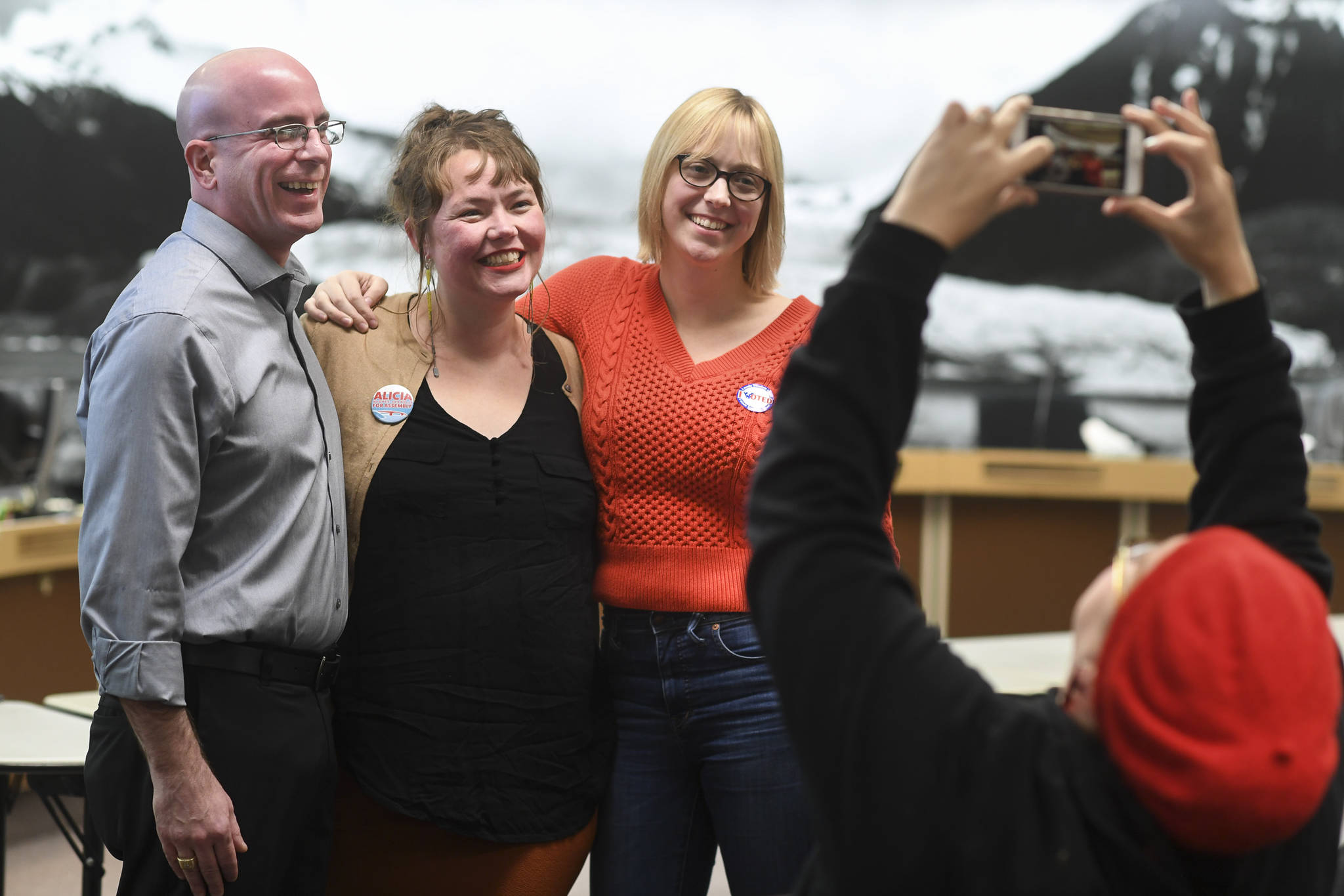 Kirsa Hughes-Skandijs takes a picture of her sister, Alicia Hughes-Skandijs, center, with Wade Bryson and Carole Triem as results come in at City Hall on Tuesday, Oct. 1, 2019. (Michael Penn | Juneau Empire)