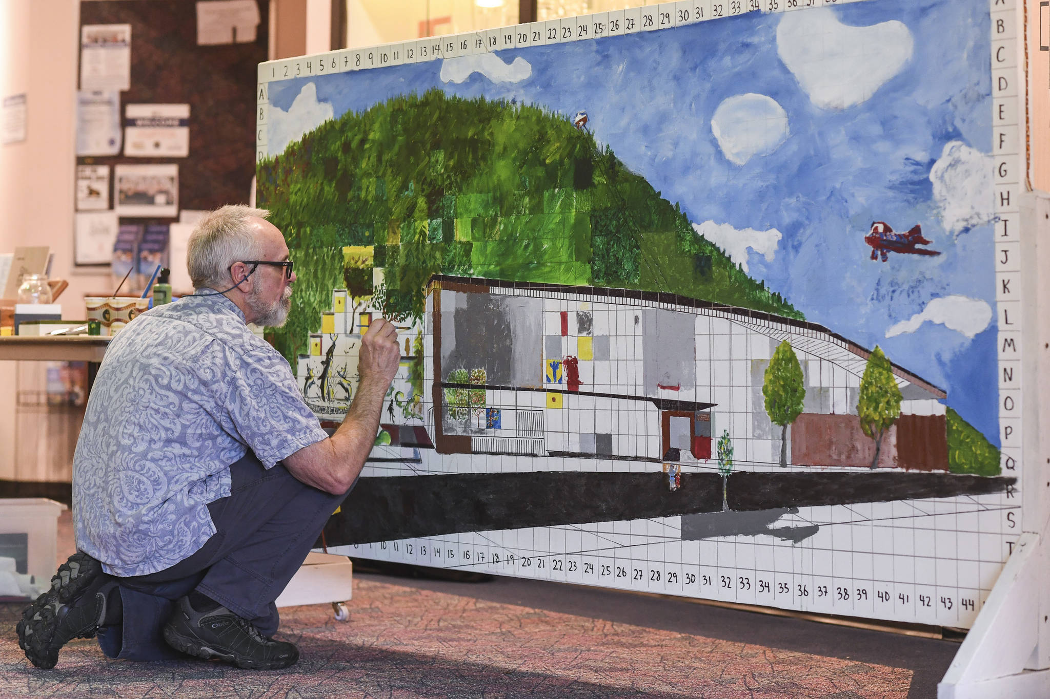 Ron Kreher paints in the squares of a new Juneau Arts and Culture Center representation in Centennial Hall during First Friday on Oct. 4, 2019. (Michael Penn | Juneau Empire)